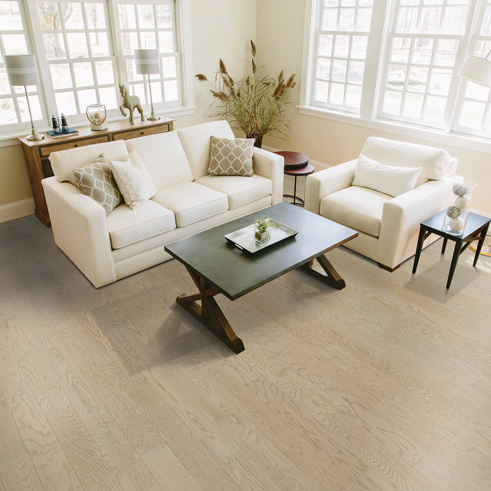 A living room with white furniture and large windows.