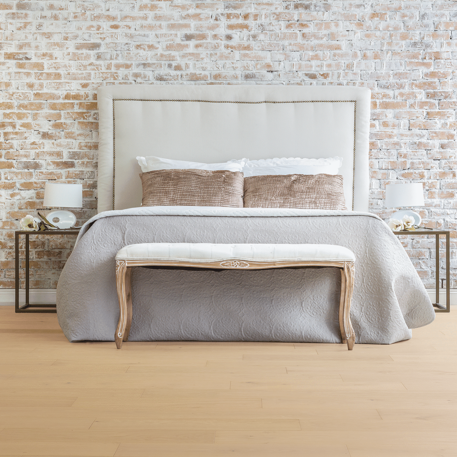 A bed with two tables and a bench in front of it