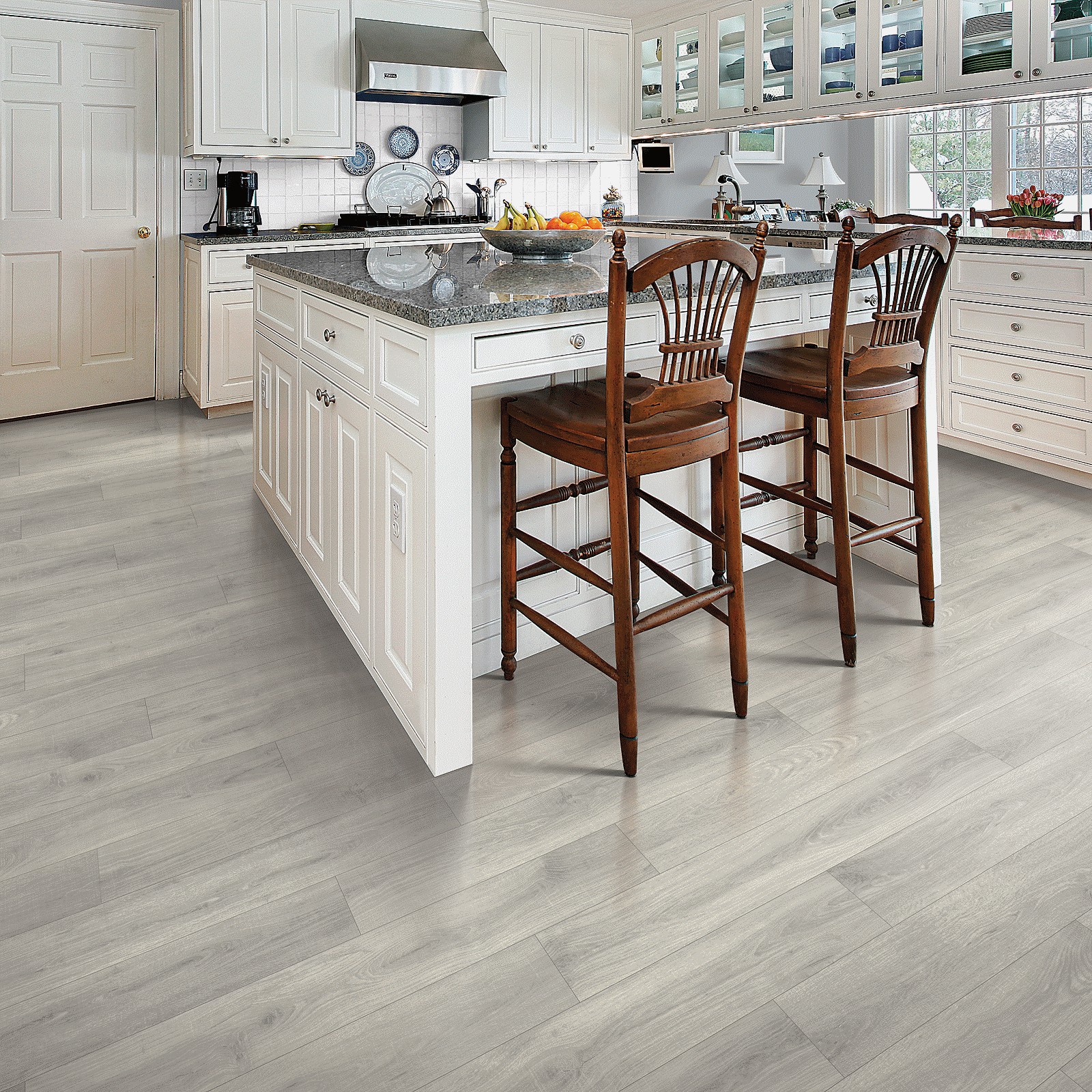 A kitchen with white cabinets and wood floors.