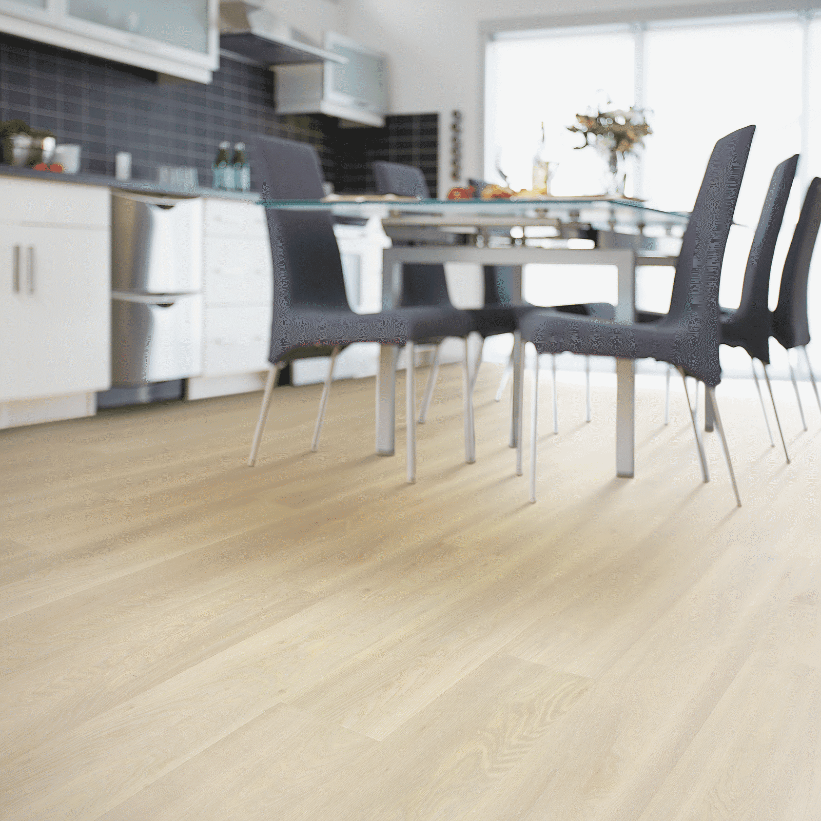 A dining room table and chairs in front of a kitchen.