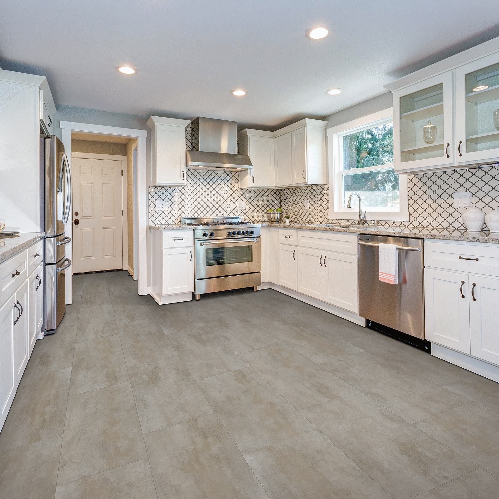 A kitchen with white cabinets and tile floors.