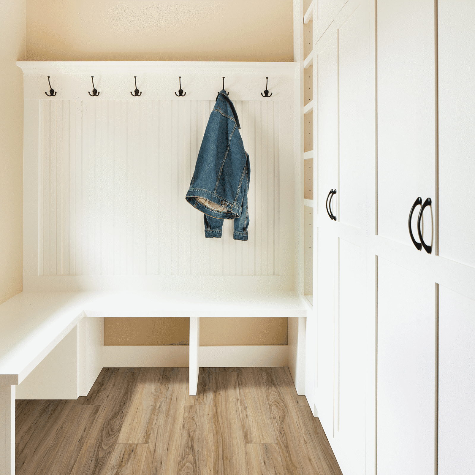 A white room with a bench and coat rack.