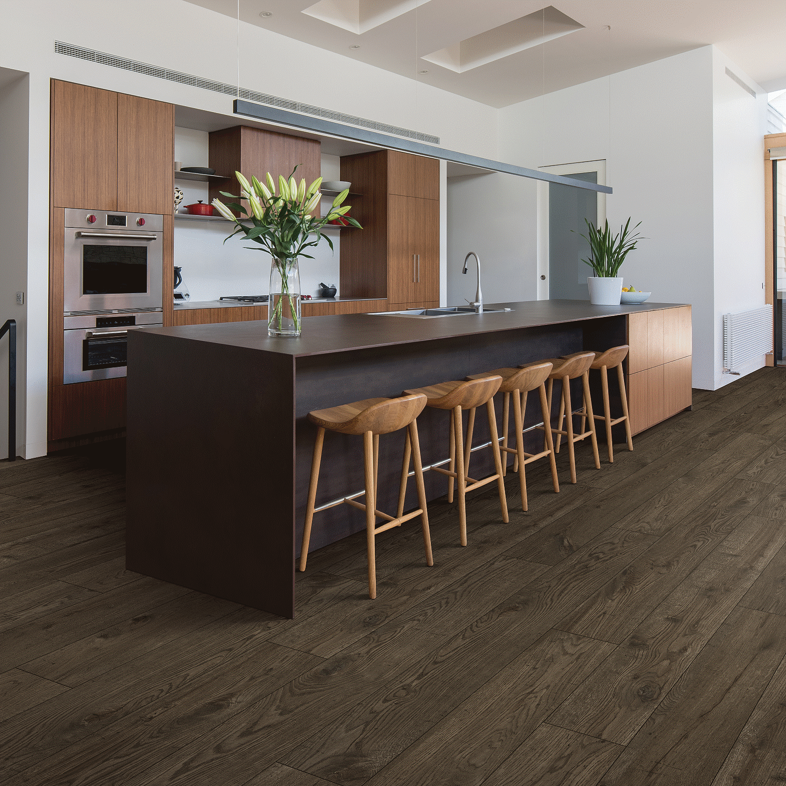 A kitchen with dark wood floors and brown cabinets.