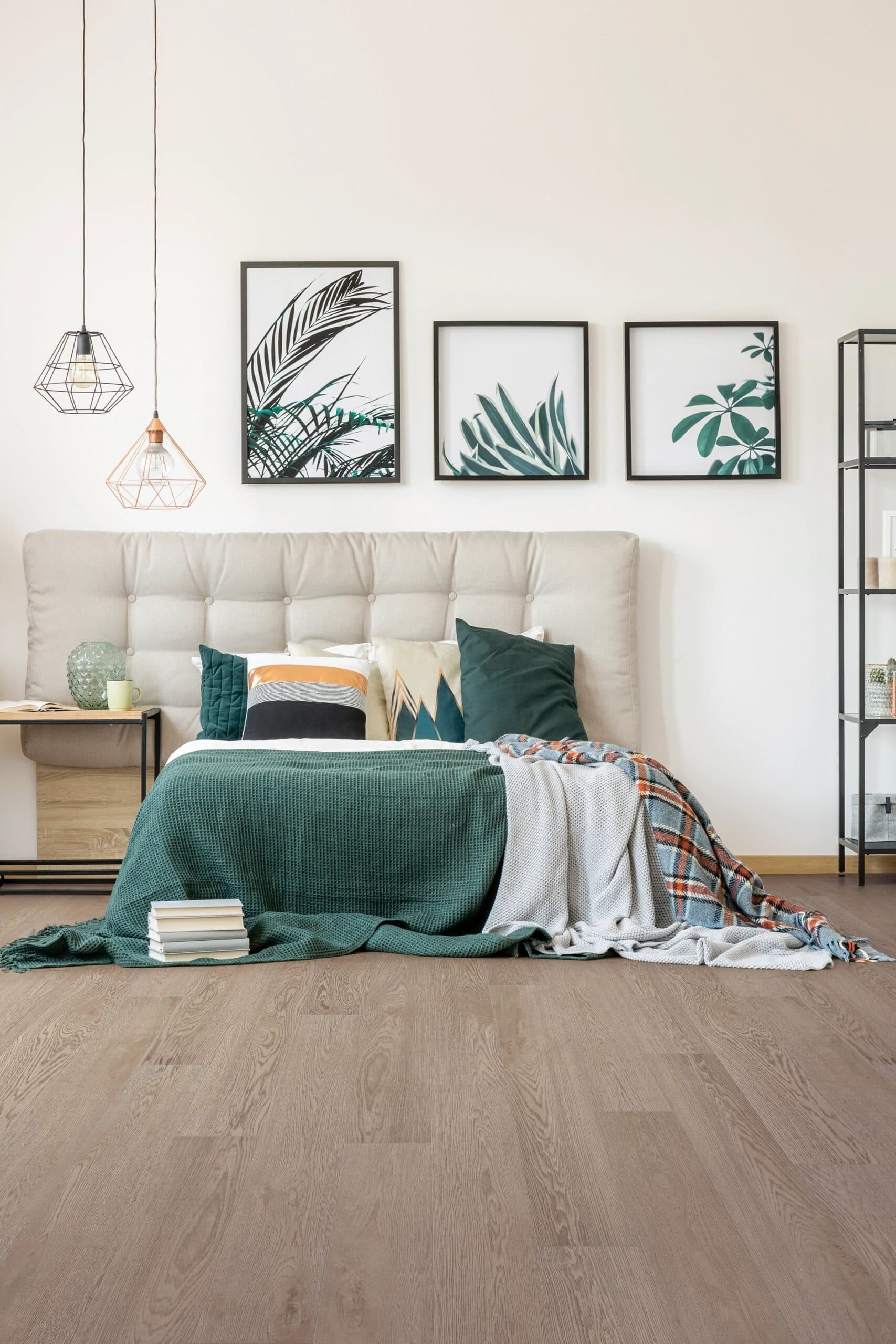 A bedroom with a bed, nightstand and wall hangings.