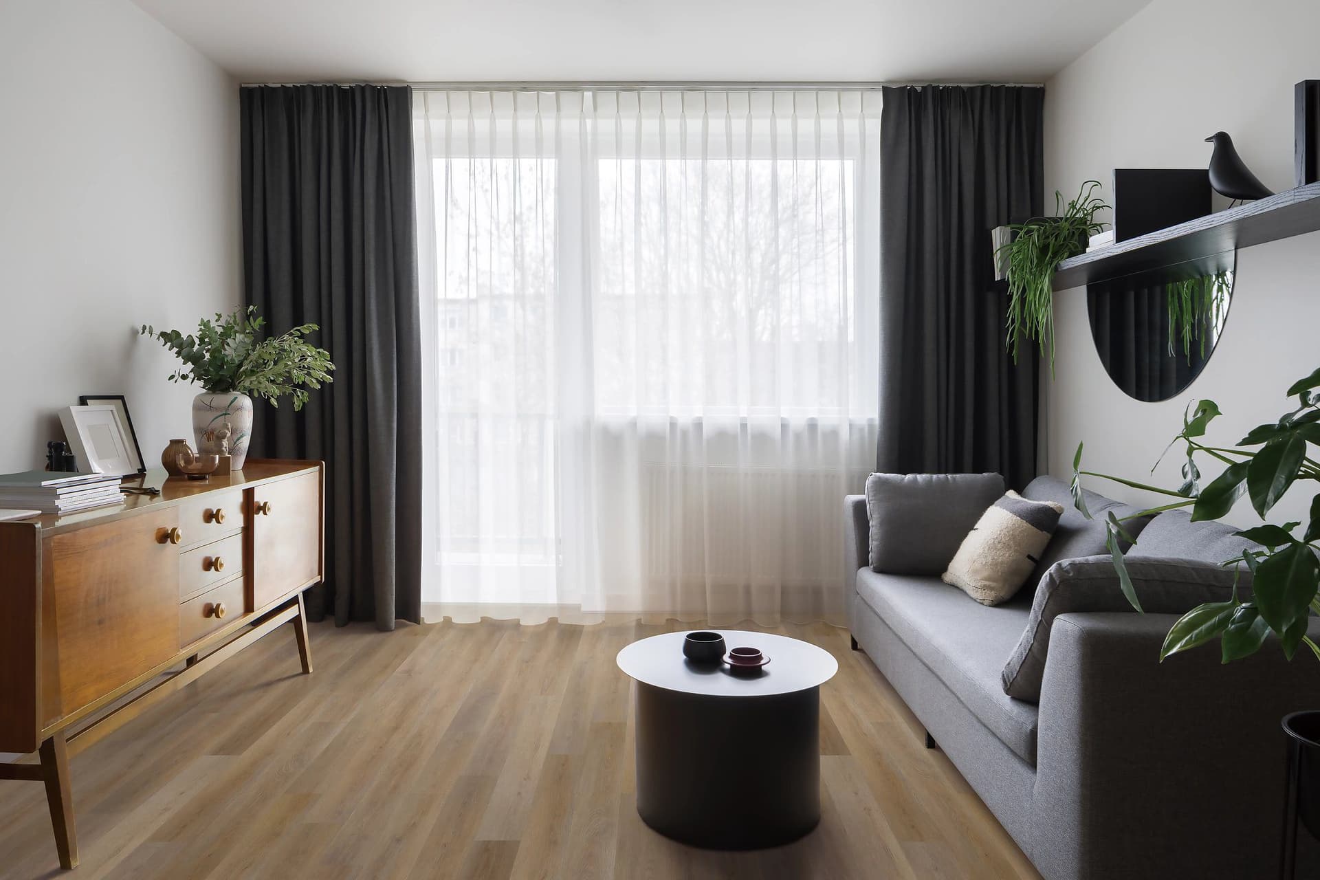 A living room with grey furniture and black curtains.