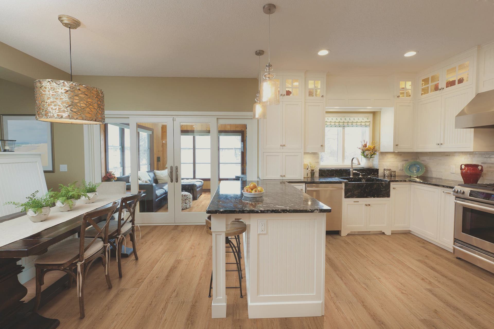 A kitchen with white cabinets and wood floors.