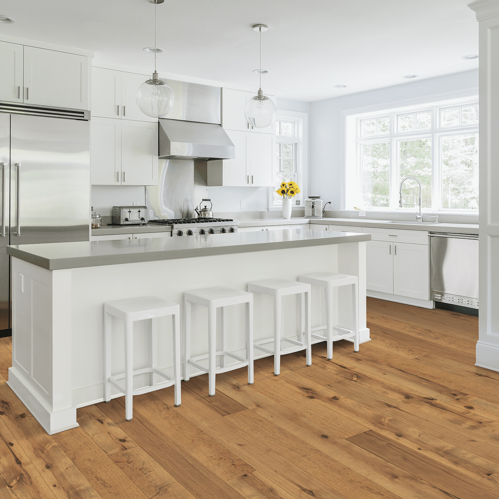 A kitchen with white cabinets and wooden floors.