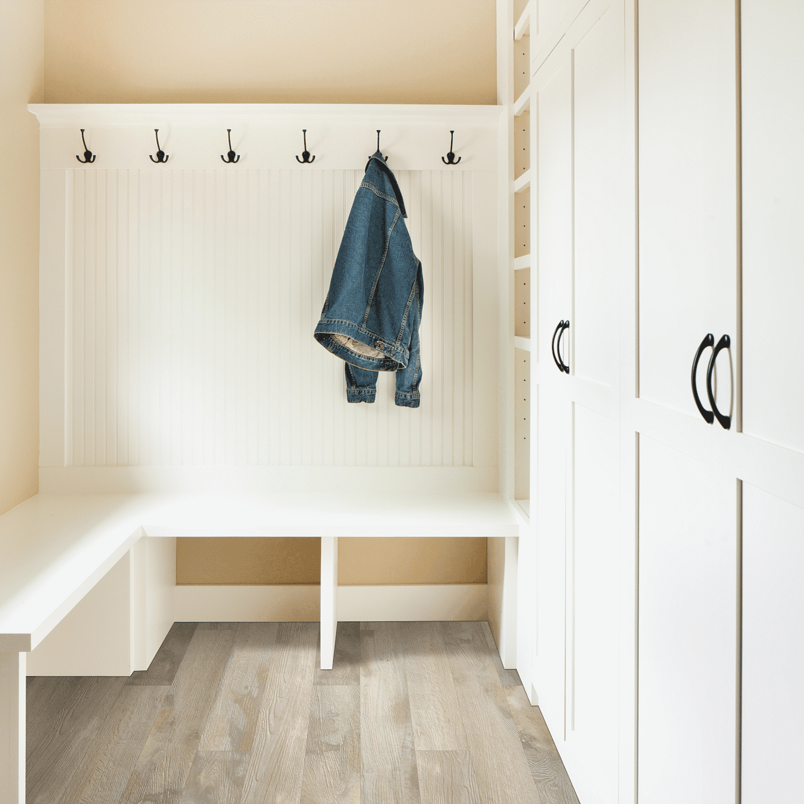 A white room with a bench and coat rack.