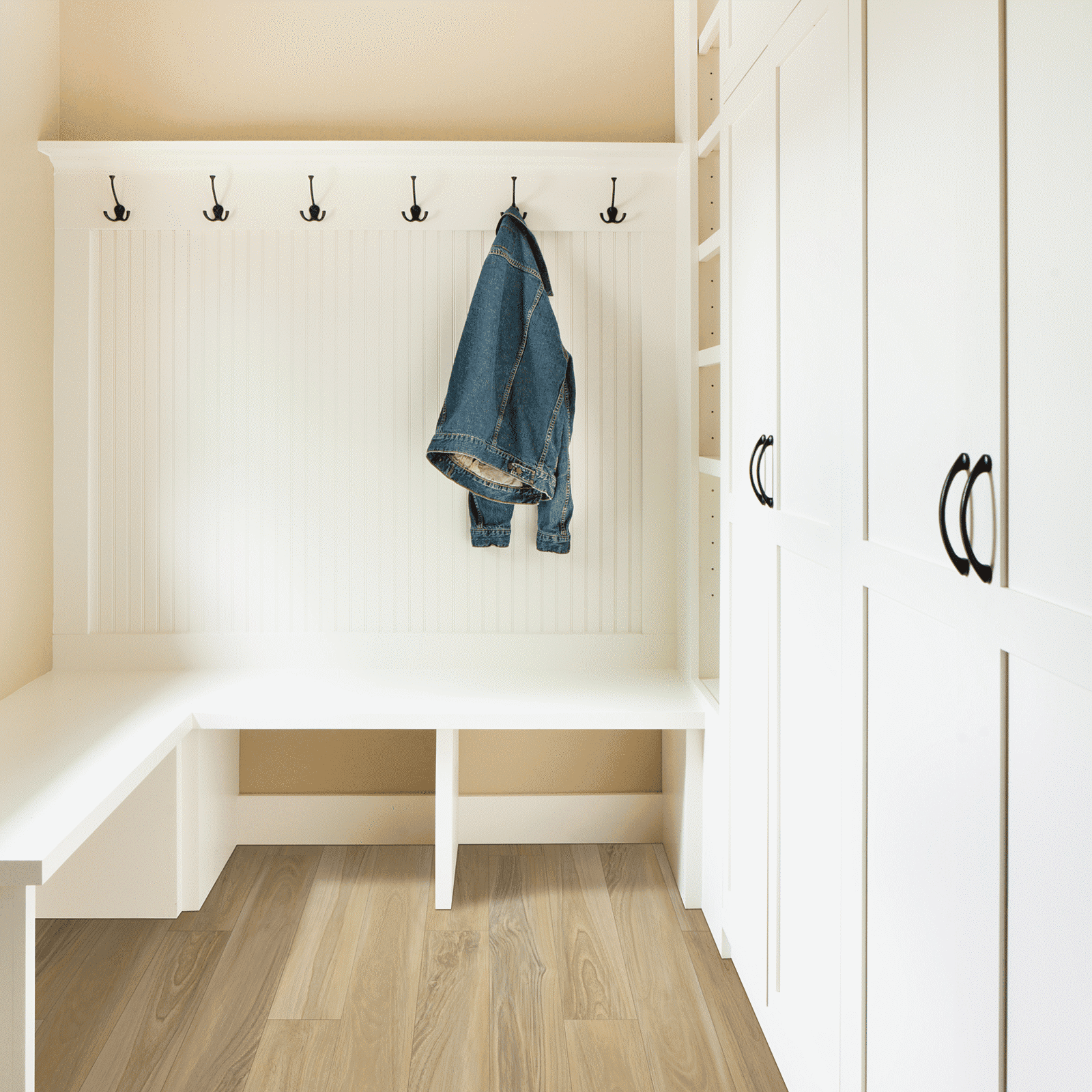 A white room with a bench and coat rack.
