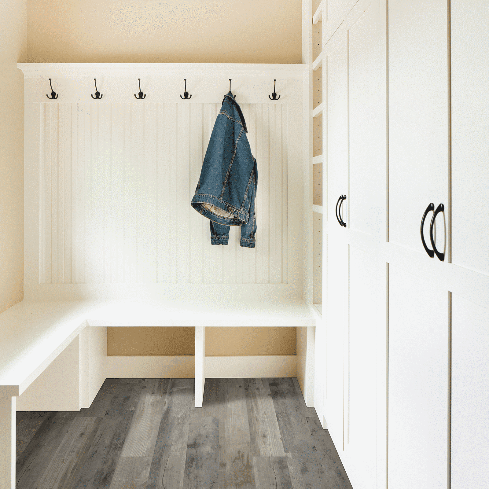 A white room with a bench and coat rack.