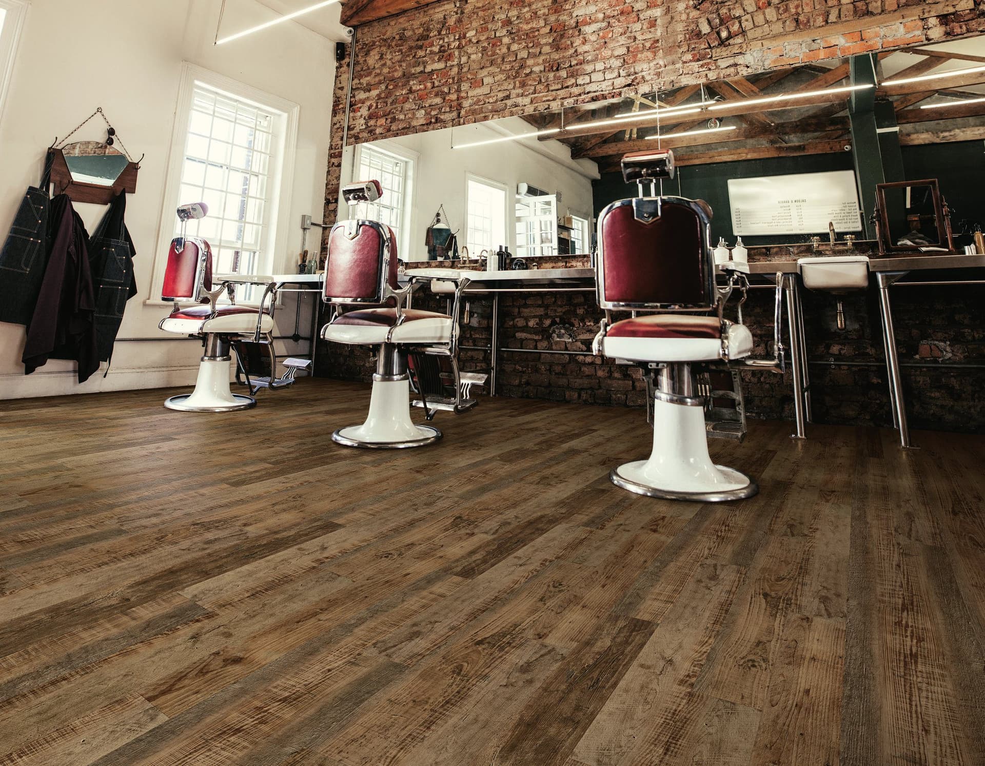 A barber shop with three chairs and two mirrors.