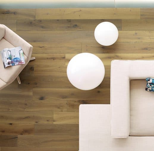 A white chair and ottoman in front of a wooden floor.