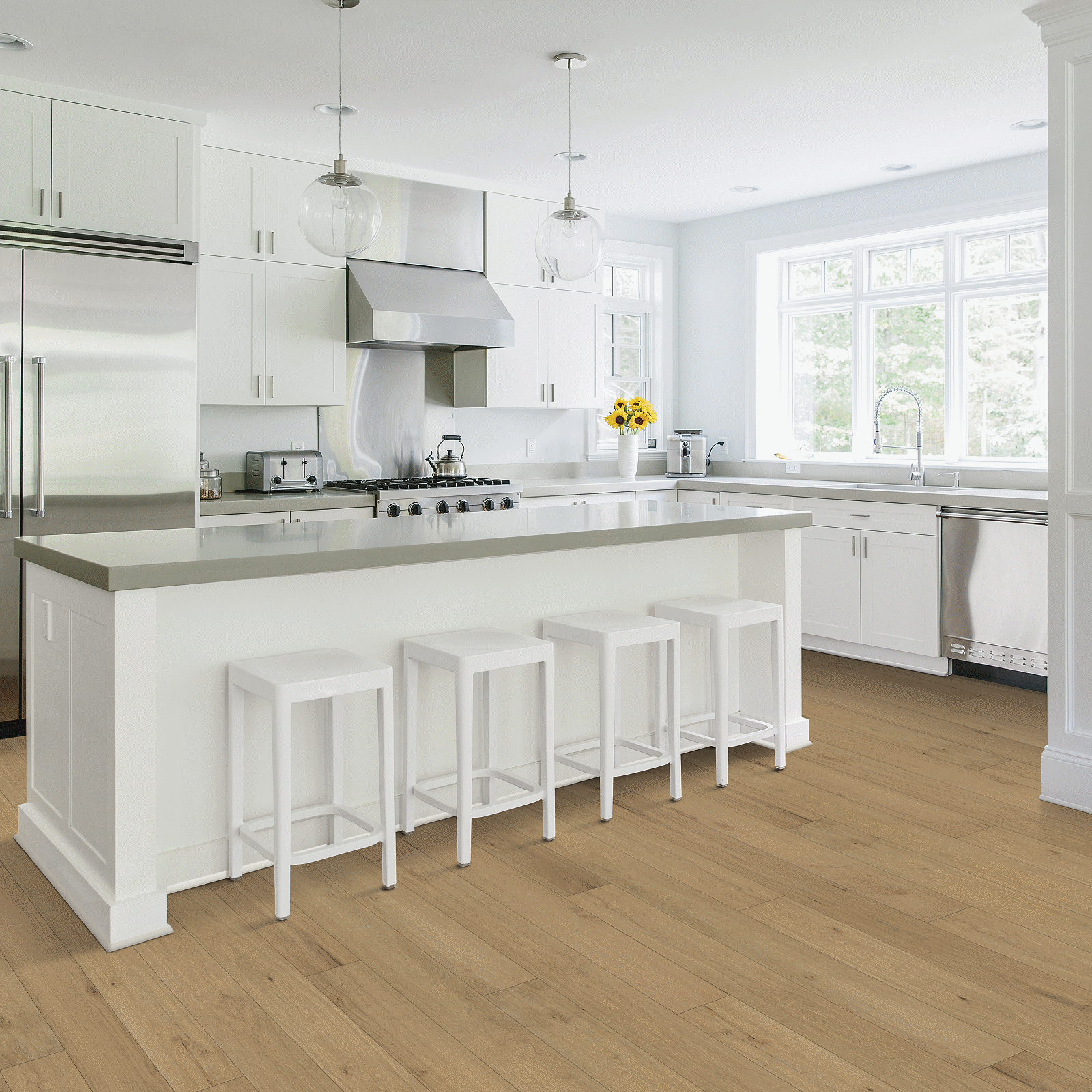 A kitchen with white cabinets and wooden floors.