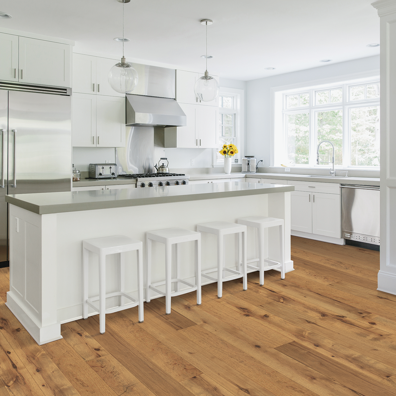 A kitchen with white cabinets and wooden floors.