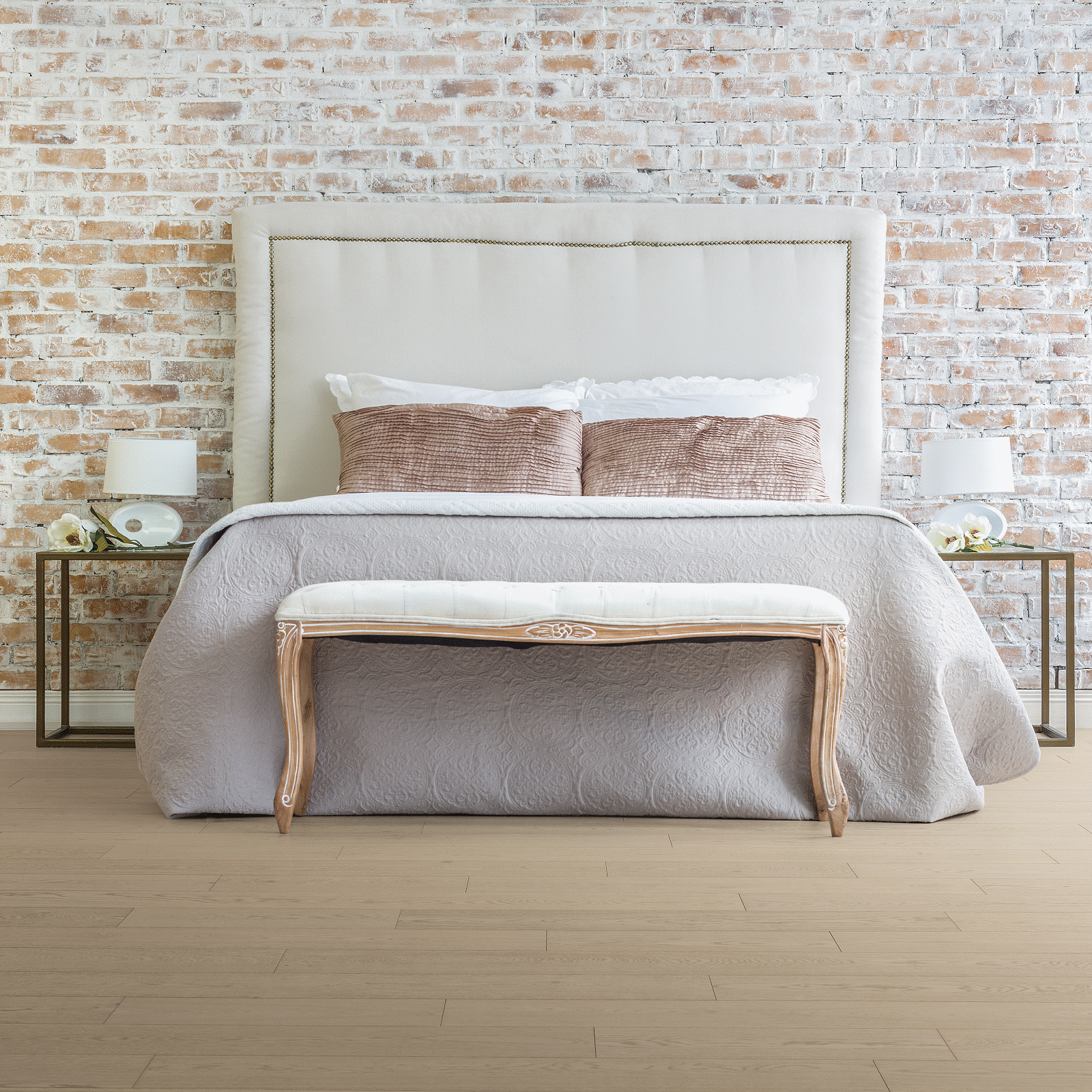 A bed with two tables and a bench in front of it