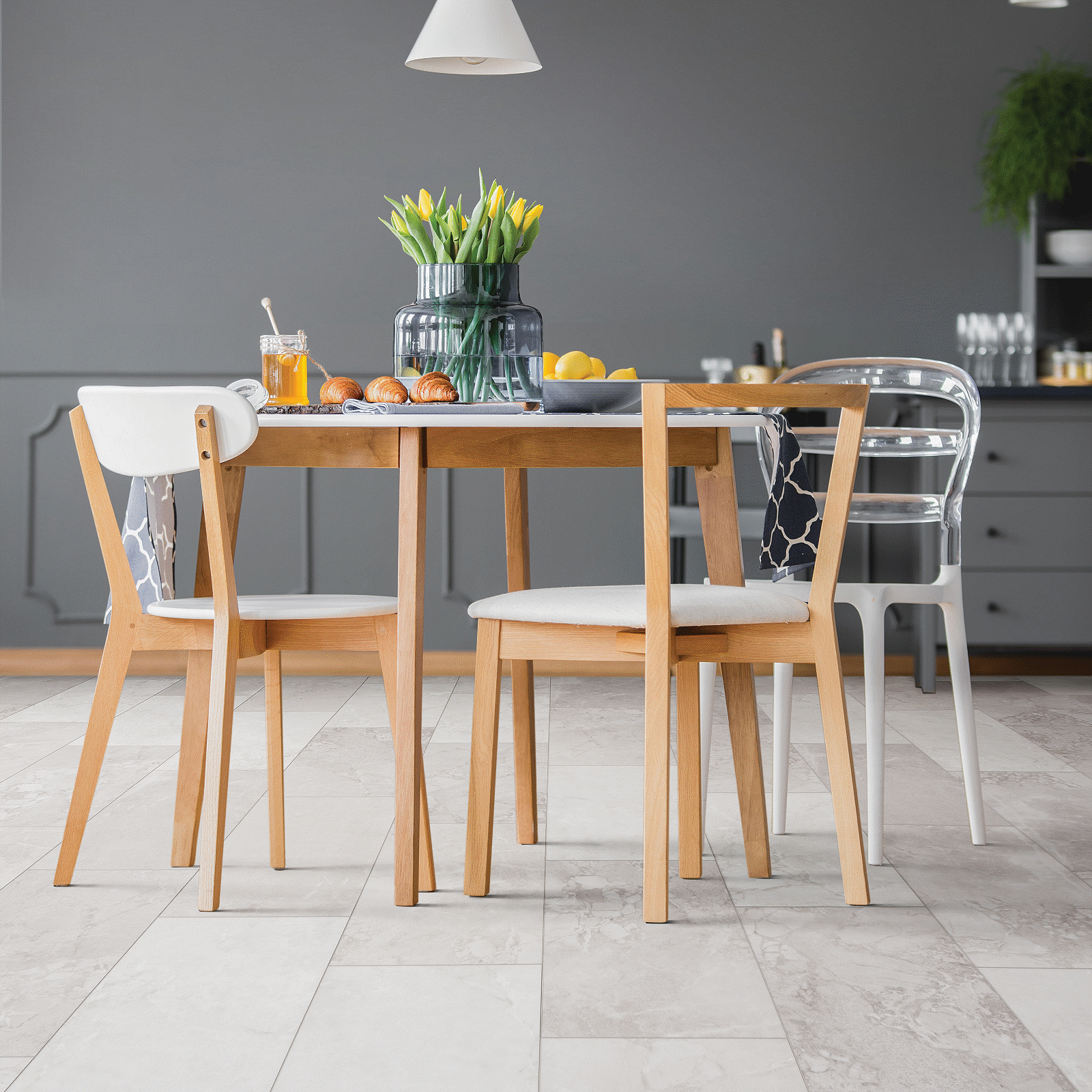 A dining room table with four chairs and a vase of flowers.