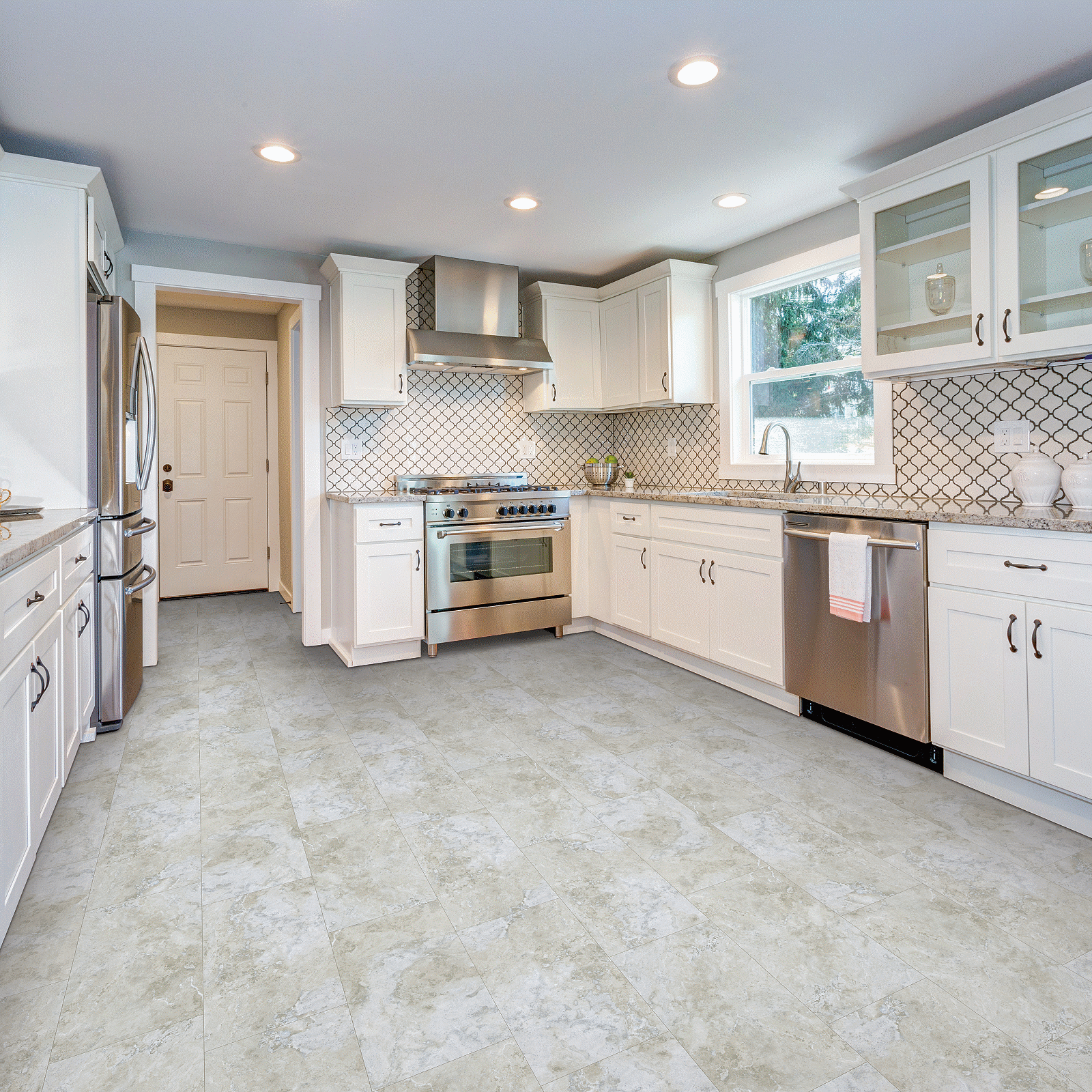 A kitchen with white cabinets and tile floors.