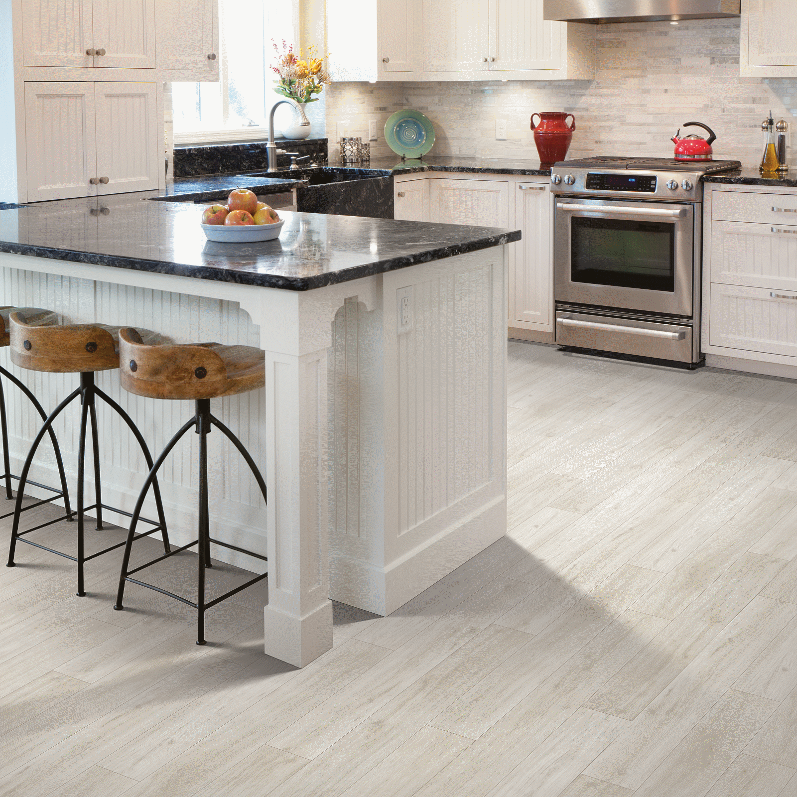 A kitchen with white cabinets and black counter tops.