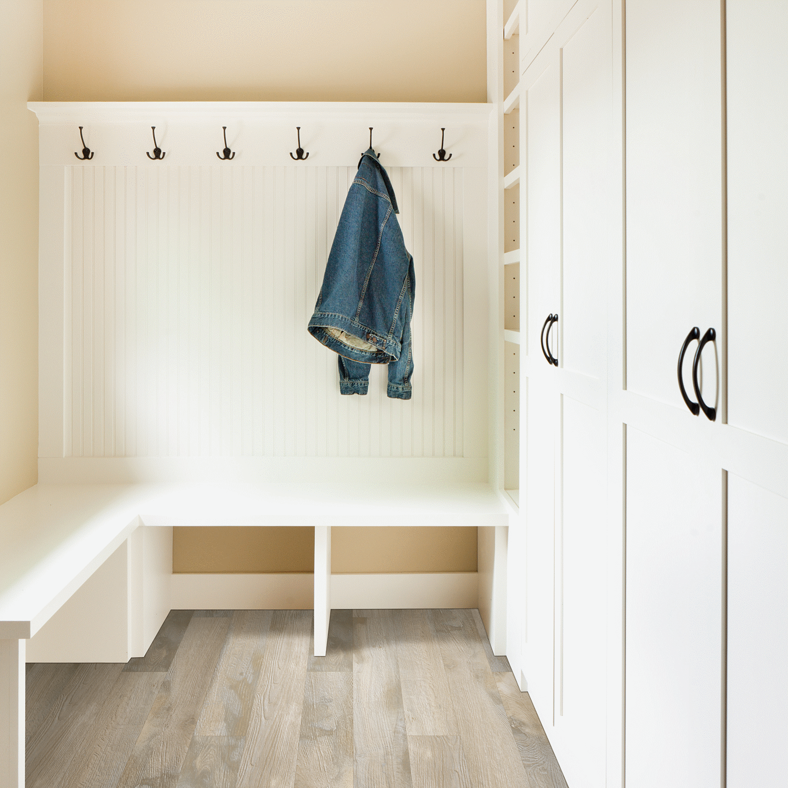 A white room with a bench and coat rack.