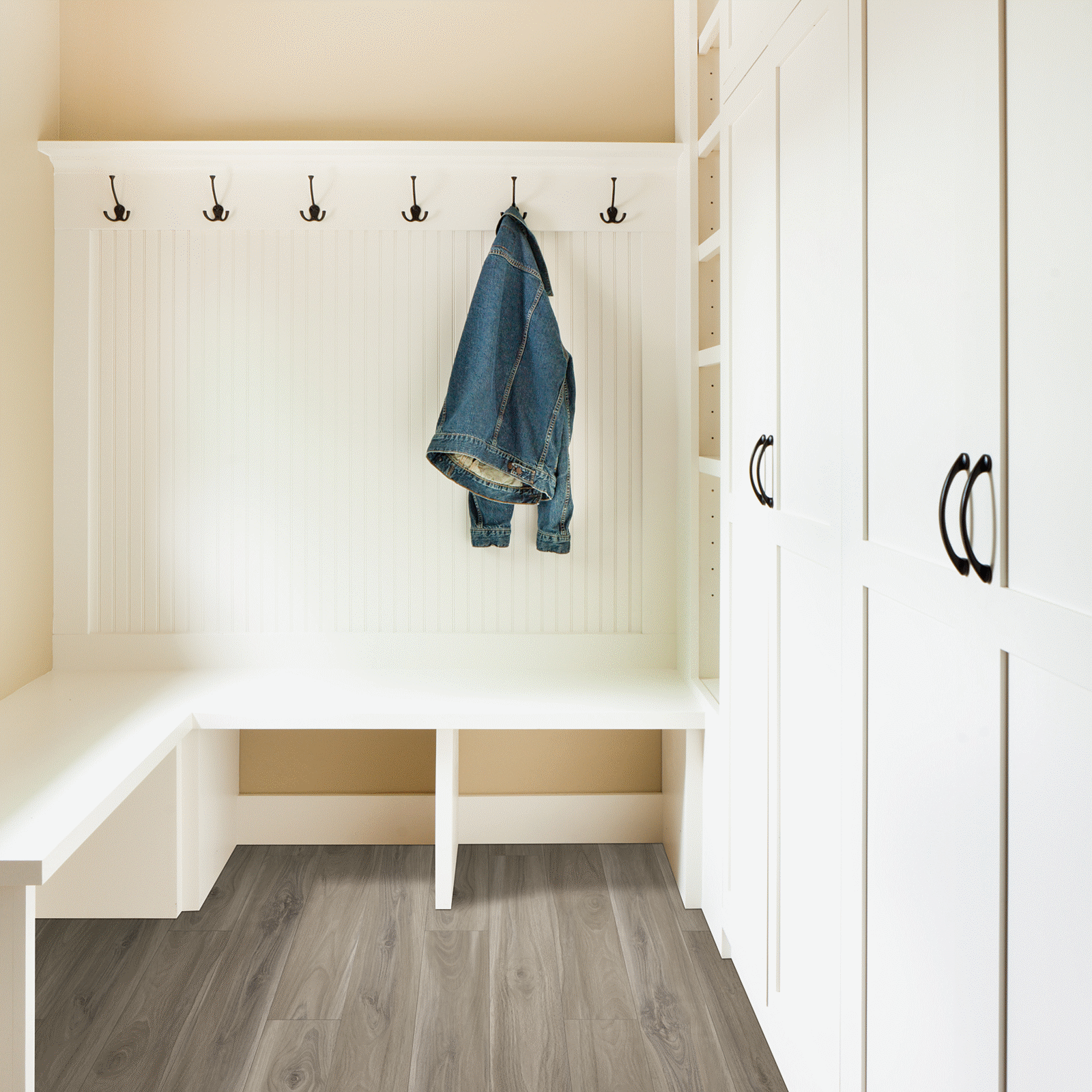 A white room with a bench and coat rack.