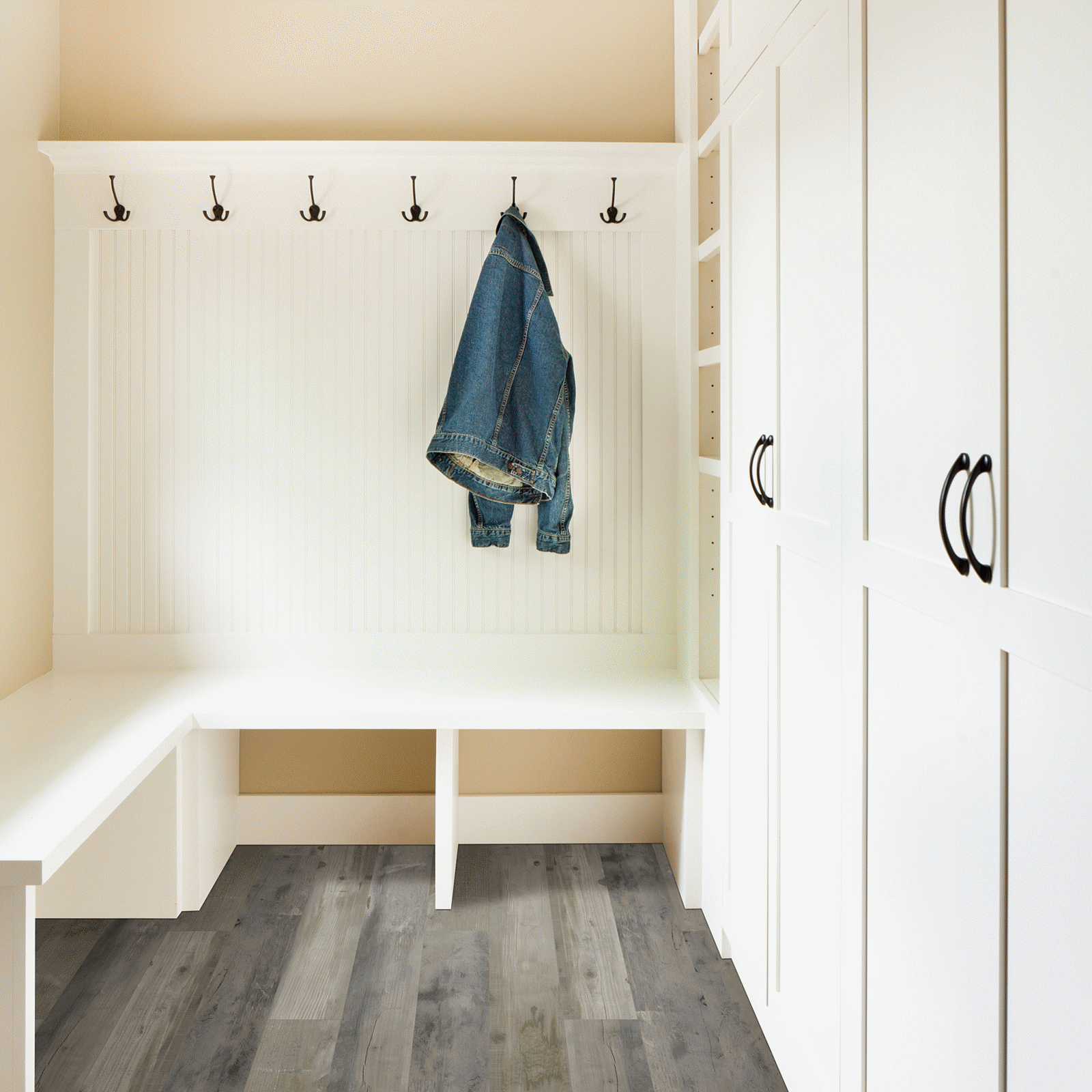 A white room with a bench and coat rack.