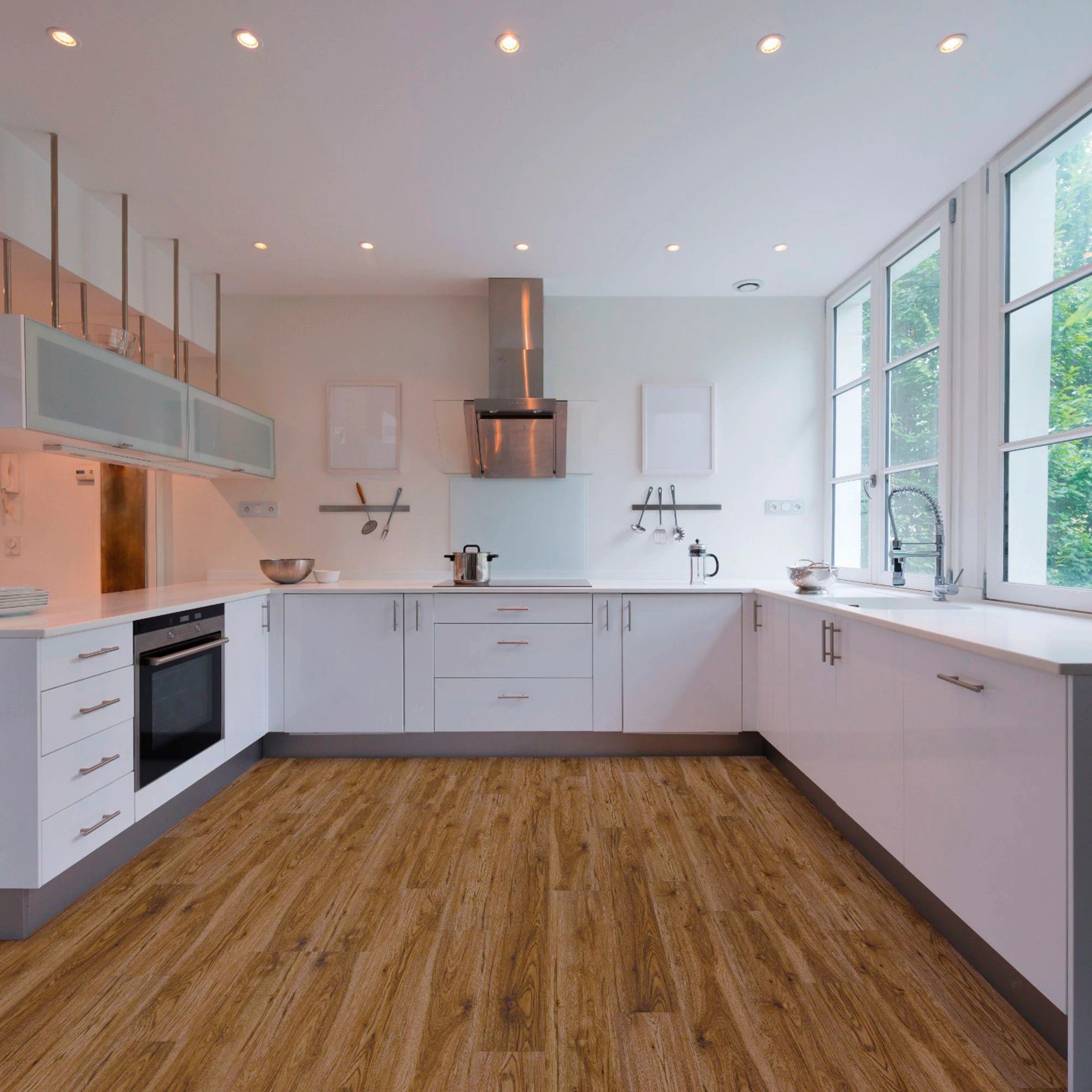 A kitchen with white cabinets and wood floors.