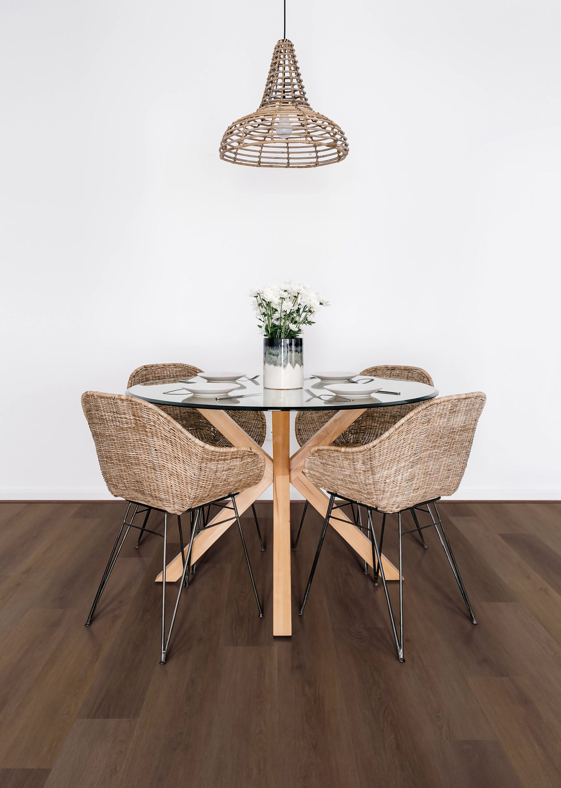 A table with four chairs and a lamp on the wall.