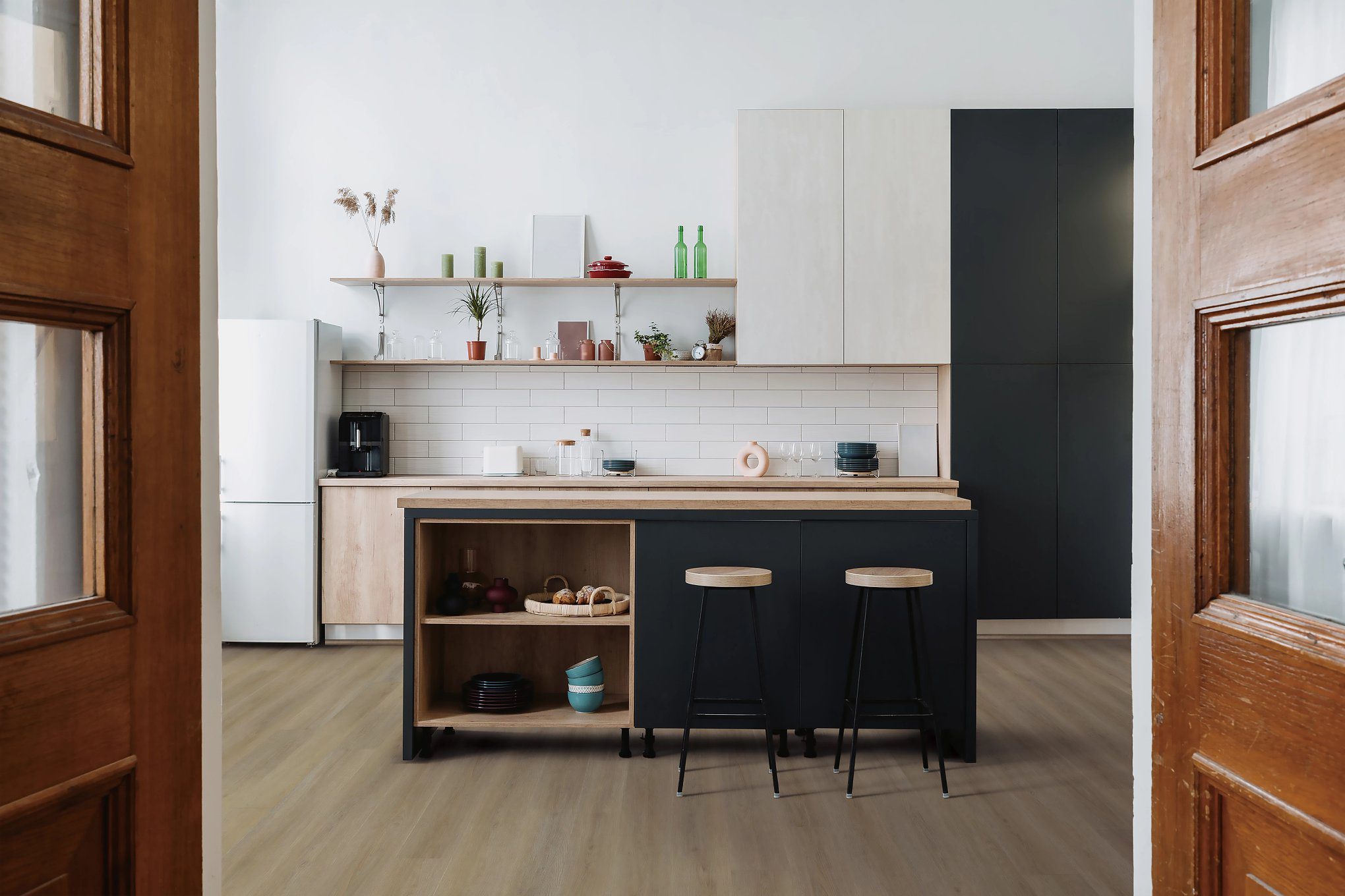 A kitchen with wooden floors and black cabinets.