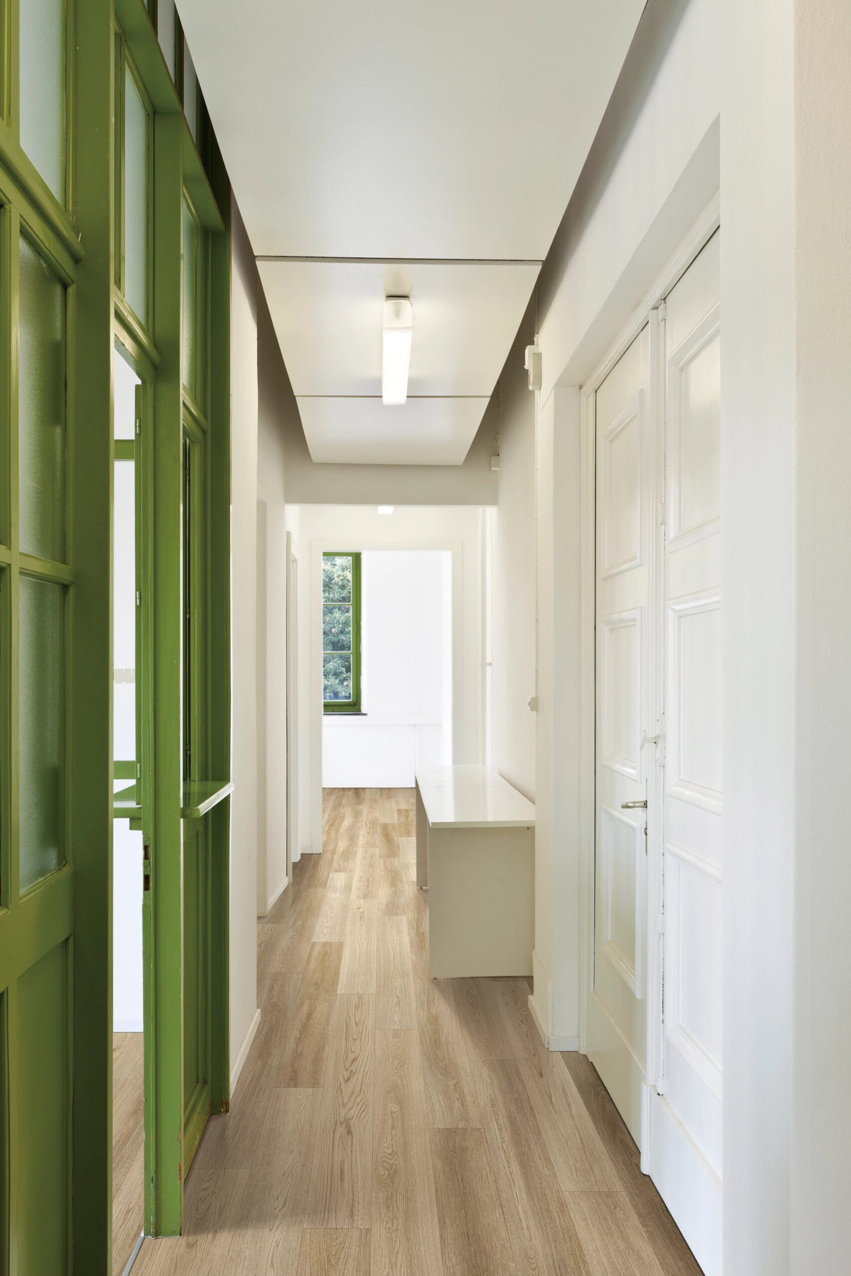 A hallway with green doors and white walls.