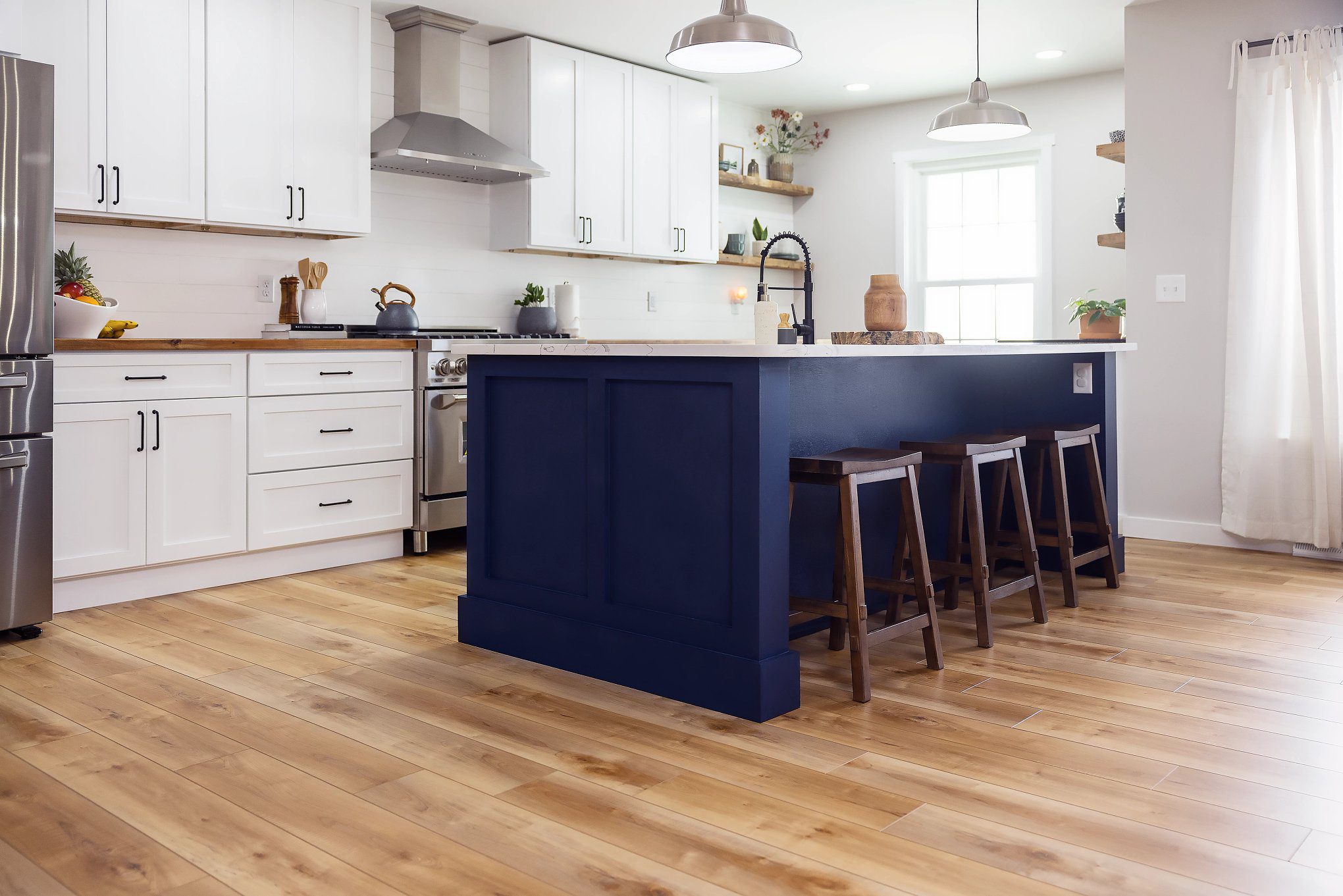 A kitchen with wooden floors and blue island.