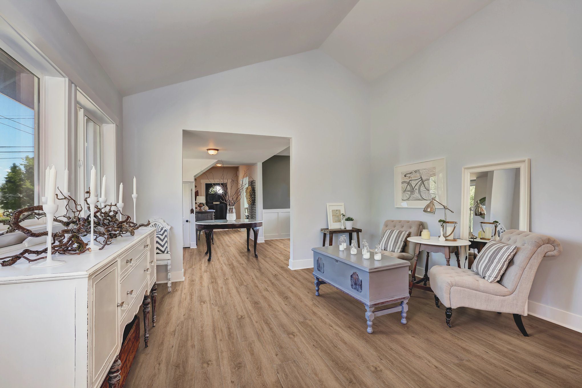 A living room with hard wood floors and white furniture.