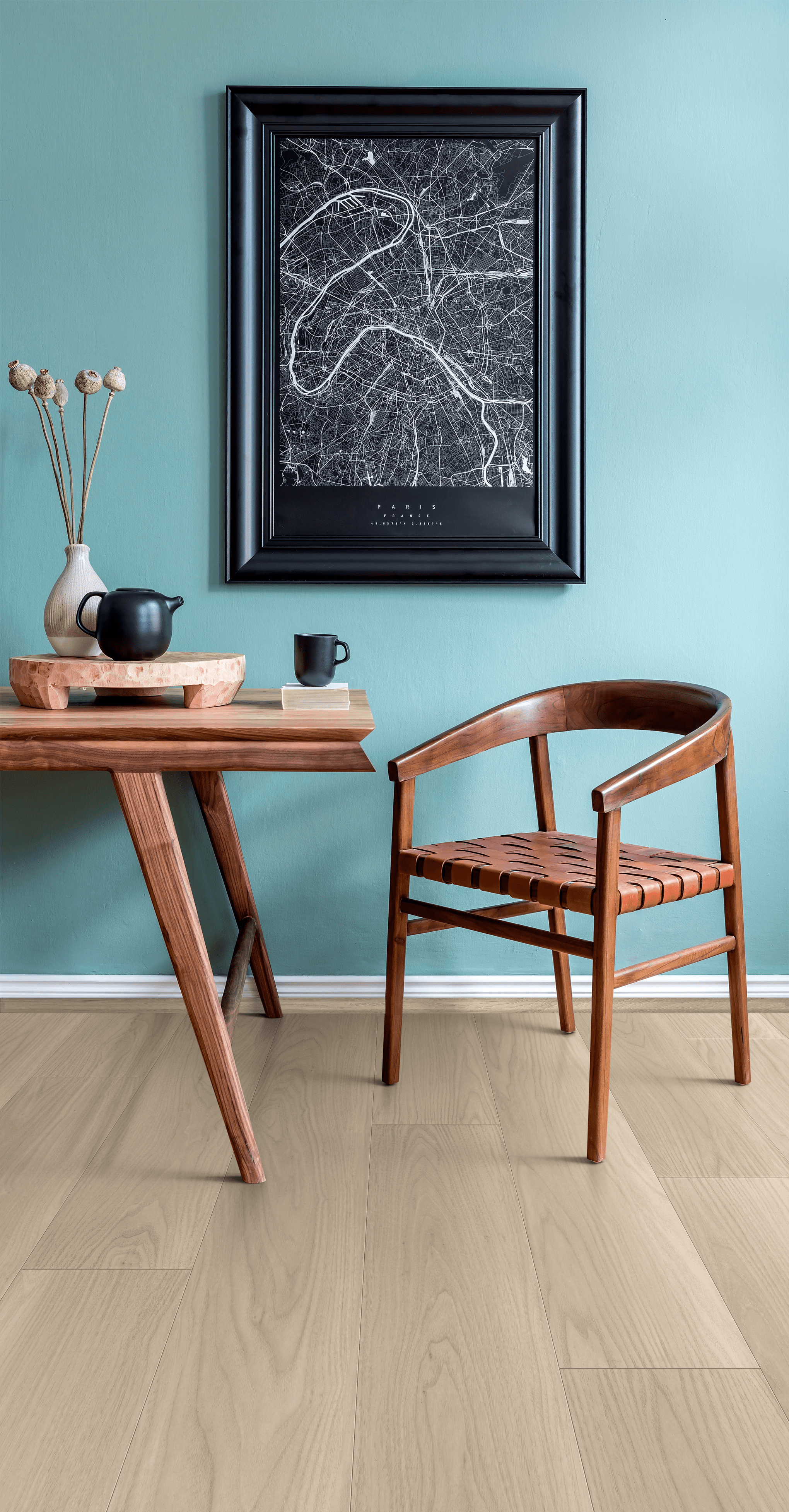 A table and chair in front of a wall with a picture on it.