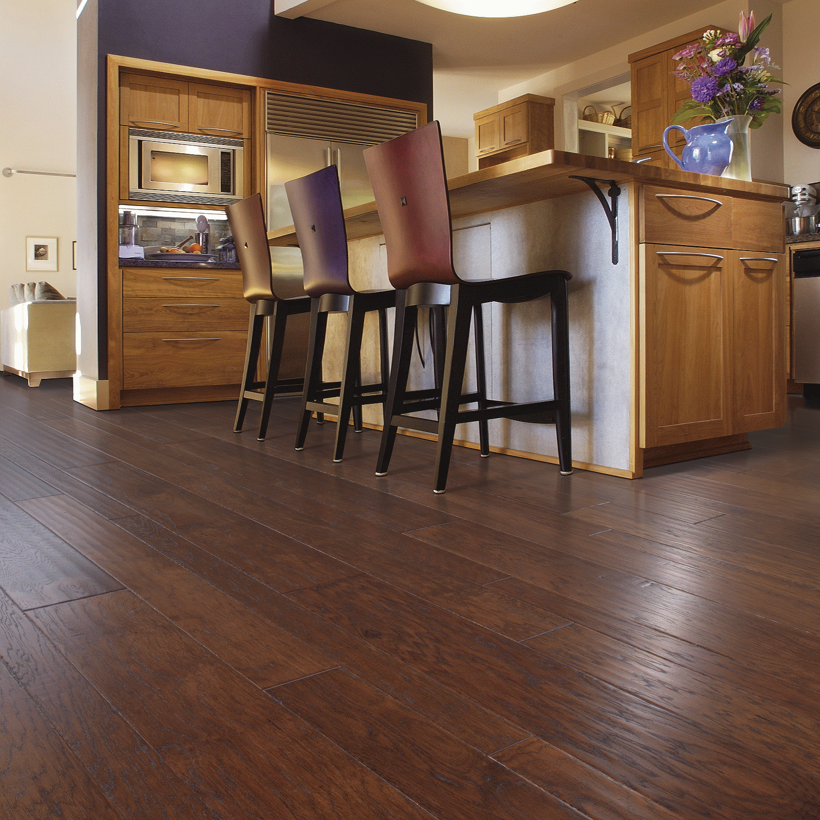 A kitchen with wooden floors and black stools.