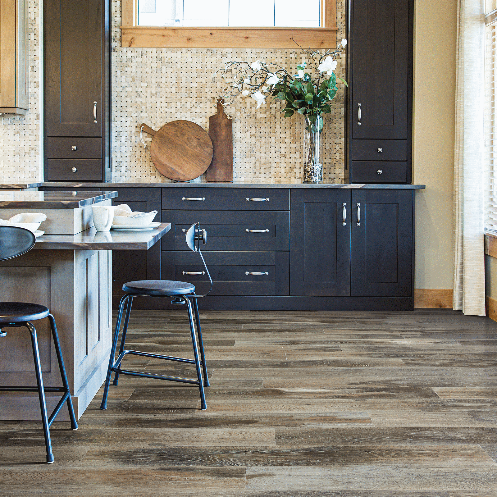 A kitchen with wooden floors and black chairs.