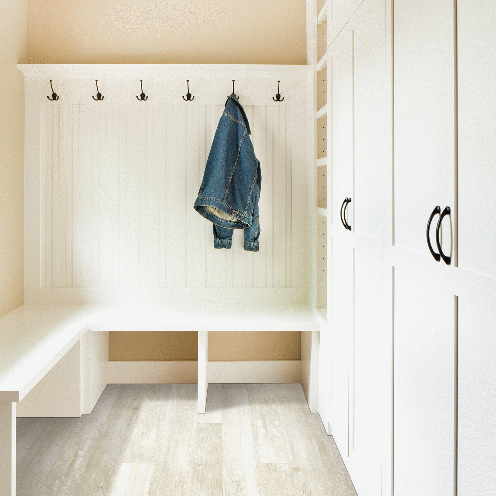 A white room with a bench and coat rack.
