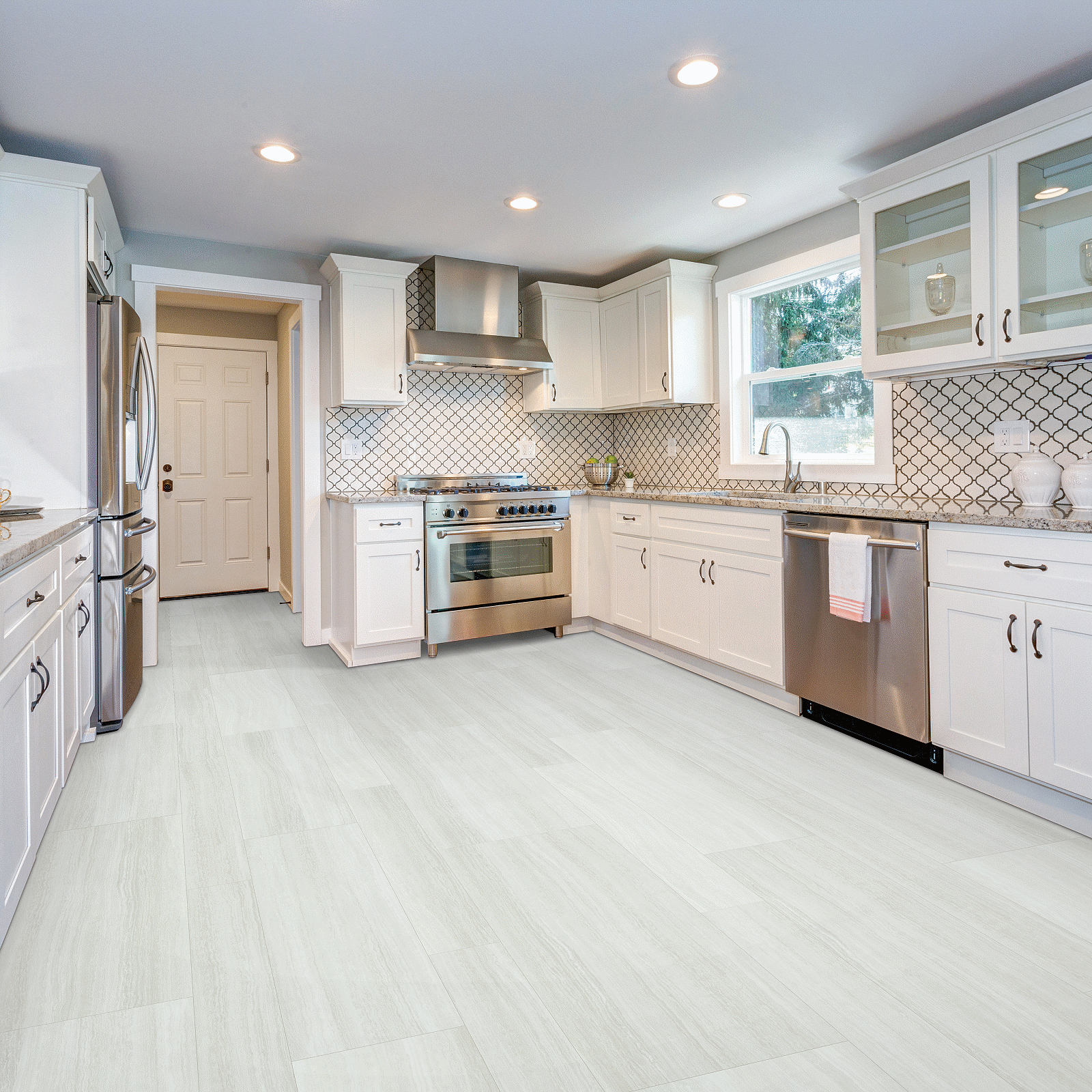 A kitchen with white cabinets and tile floors.