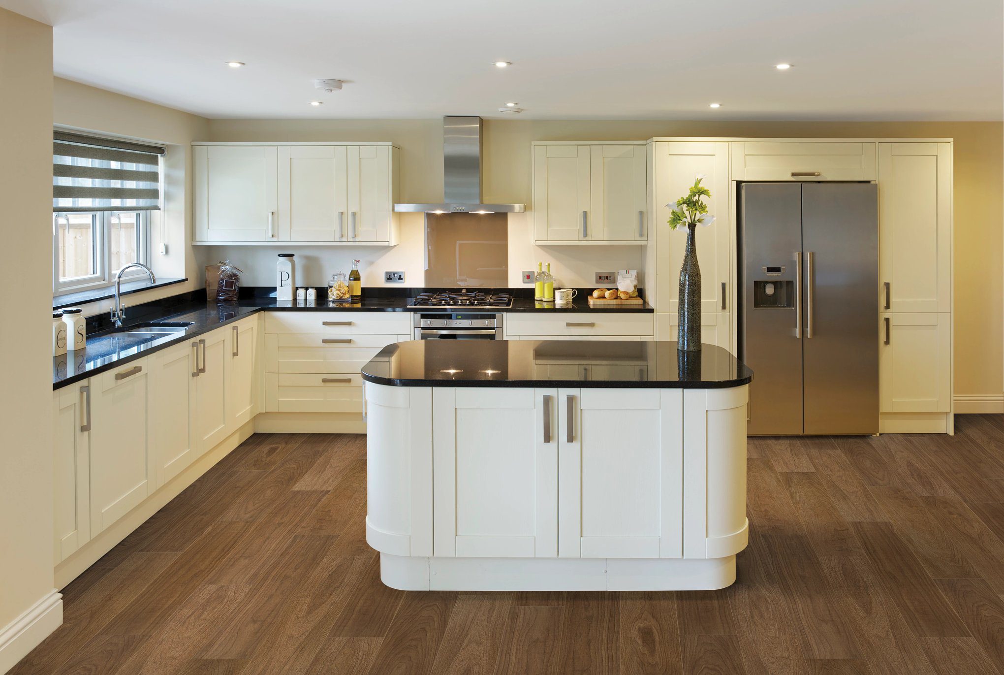 A kitchen with white cabinets and black counter tops.