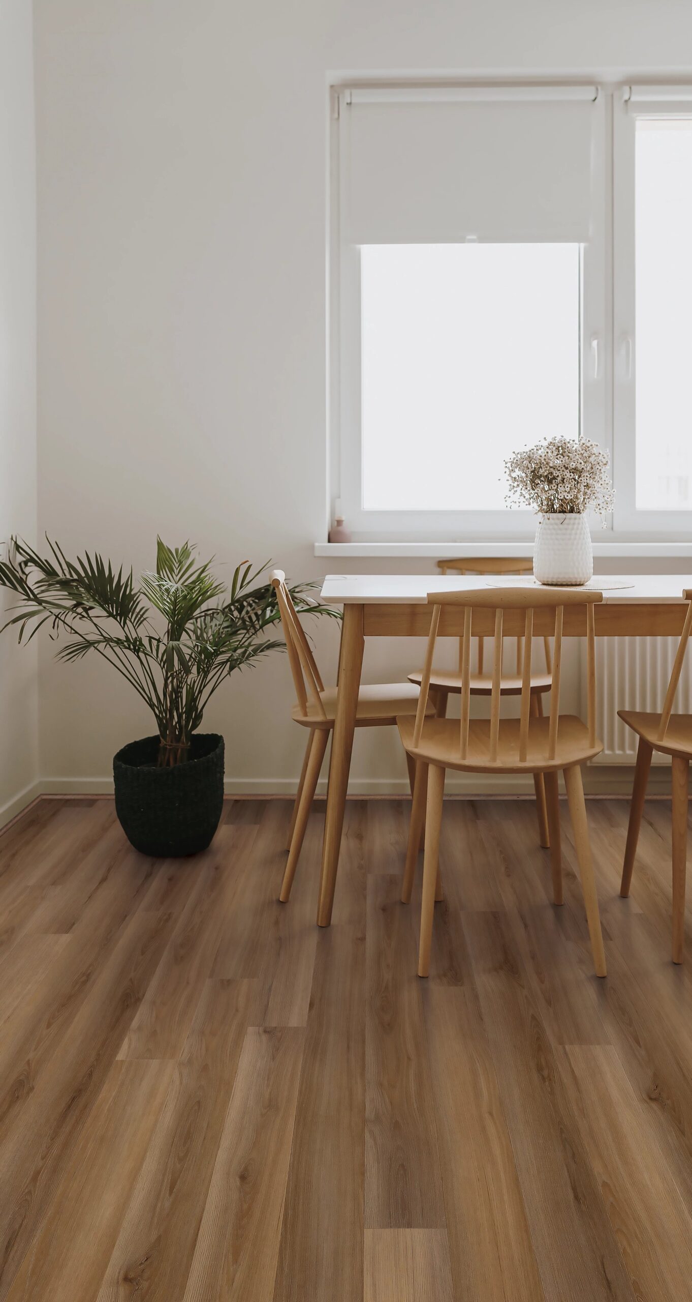 A dining room table with four chairs and a plant.