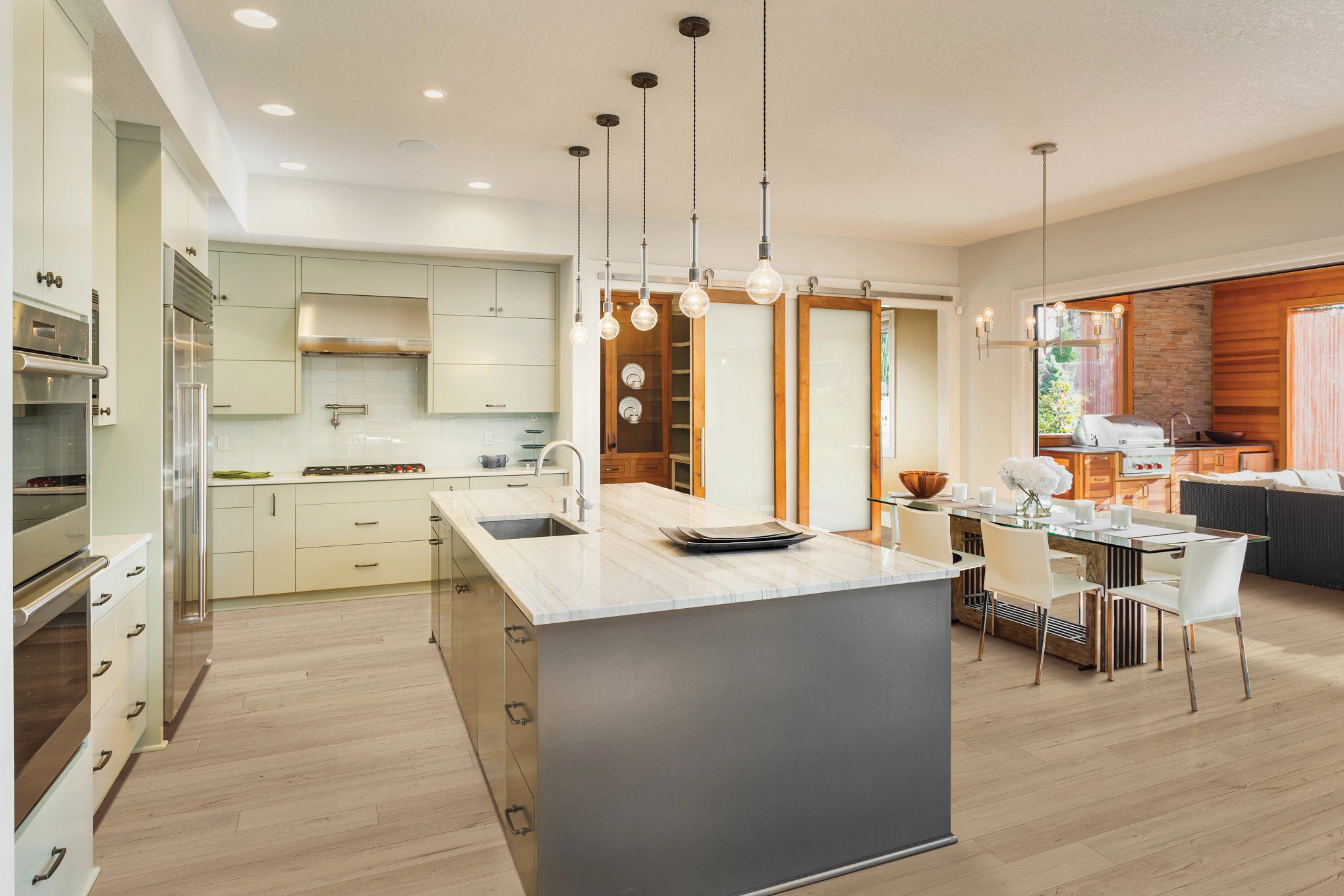 A kitchen with white cabinets and wooden floors.