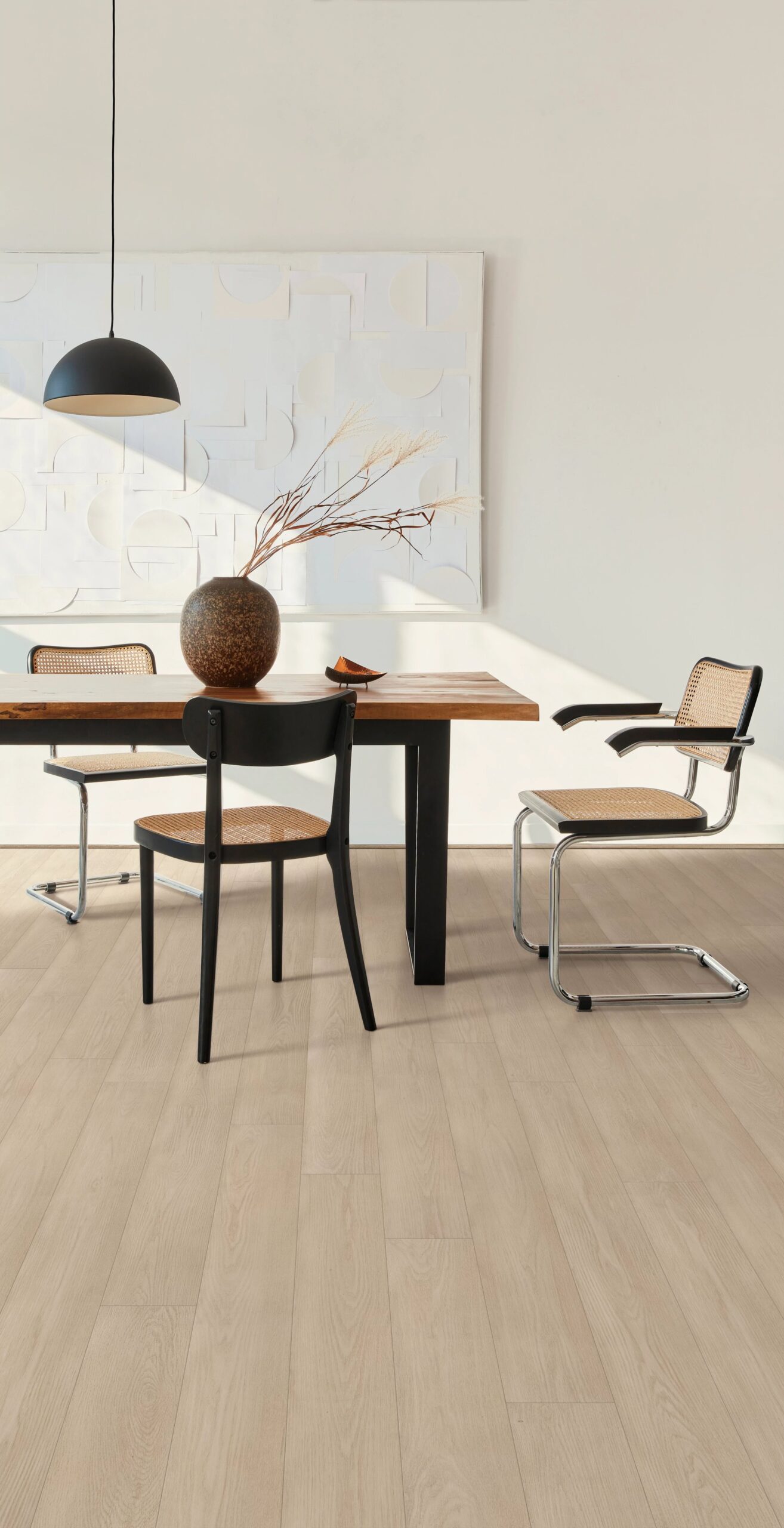 A dining room table with chairs and a vase on the floor.