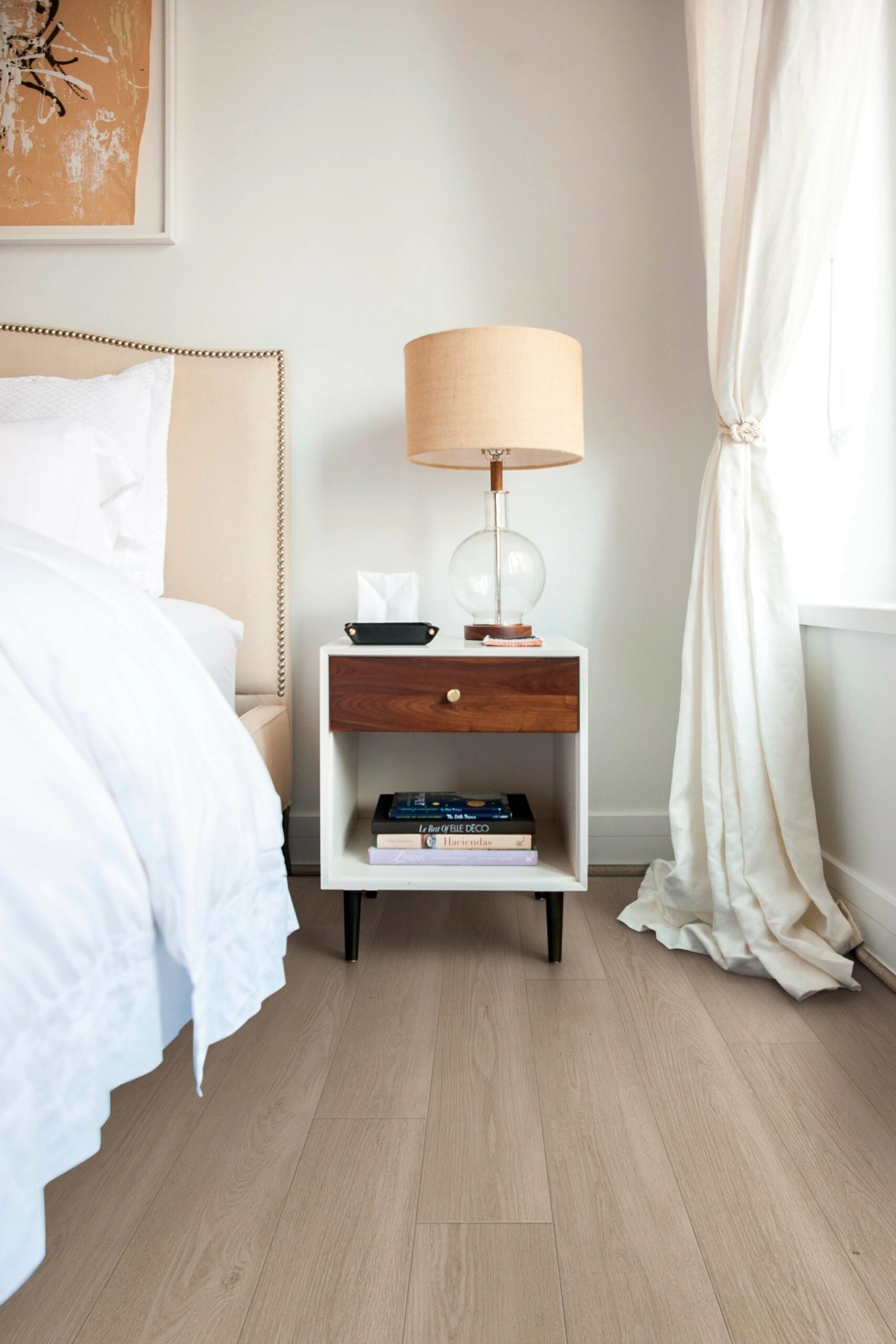 A bedroom with white walls and wooden floors.
