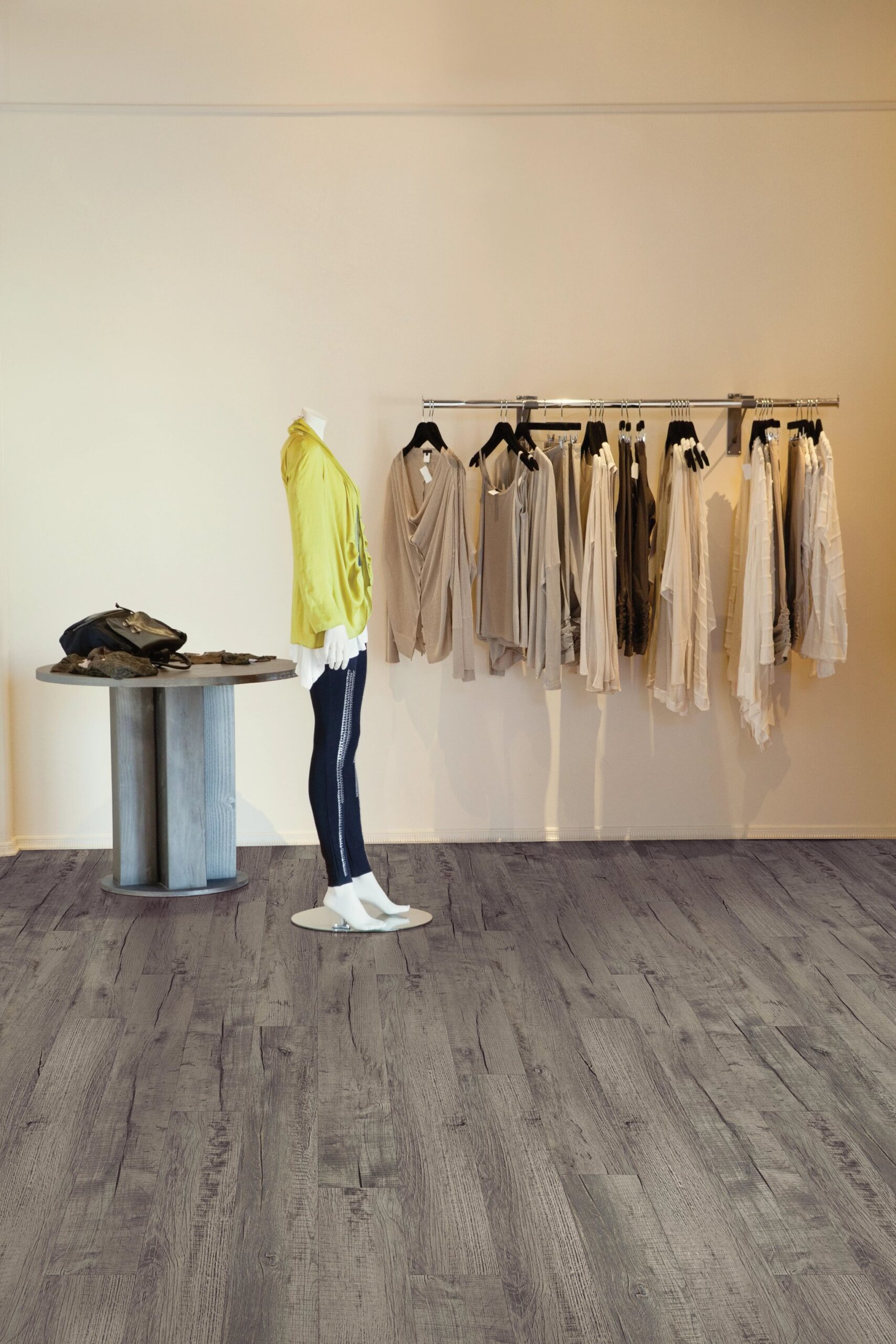 A mannequin in front of a wall with clothes hanging on it.