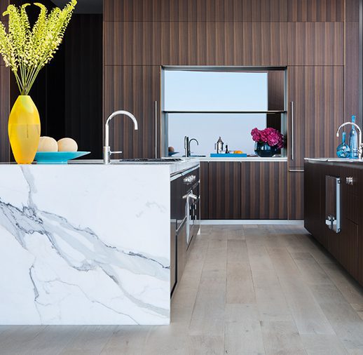 A kitchen with marble counter tops and wooden cabinets.