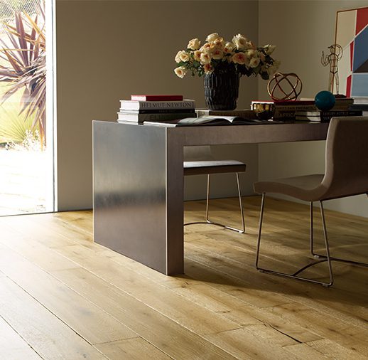 A dining room table with chairs and flowers on the floor.