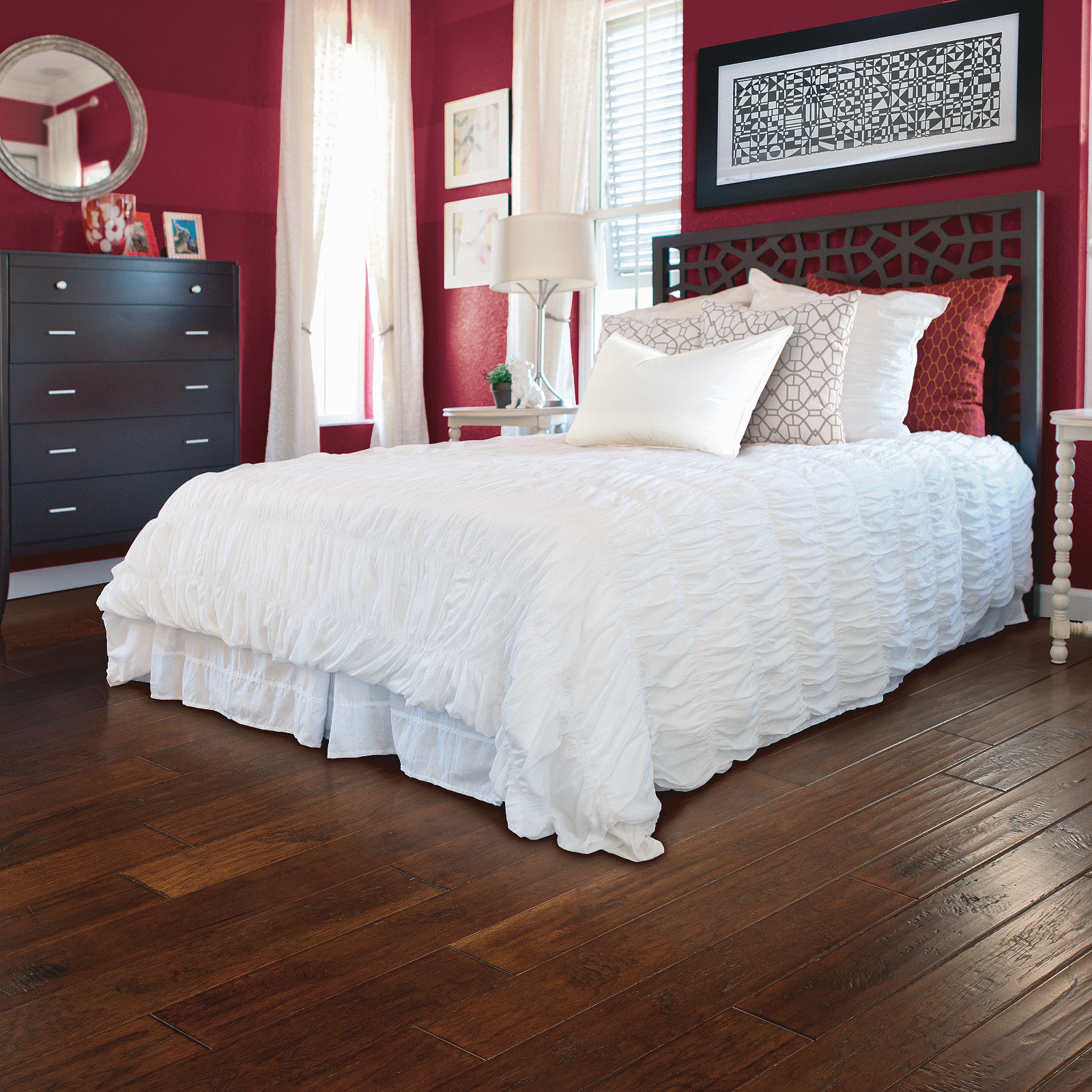 A bedroom with red walls and white bedding.