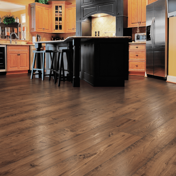A kitchen with wooden floors and black cabinets.