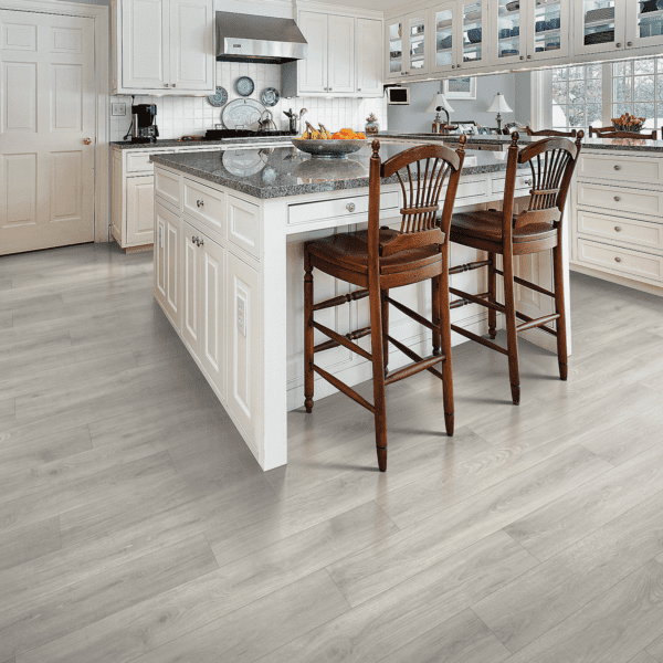 A kitchen with white cabinets and wood floors.