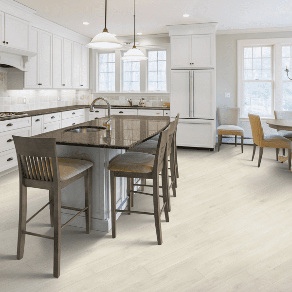 A kitchen with white cabinets and wooden floors.