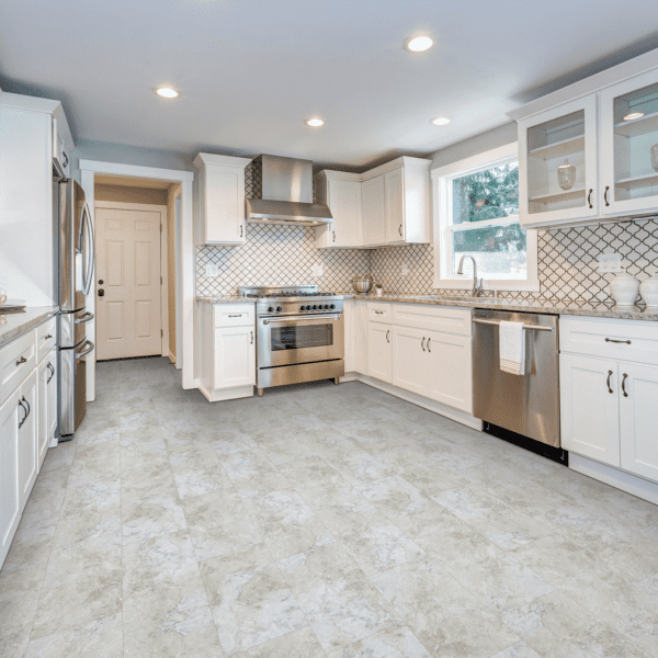 A kitchen with white cabinets and tile floors.