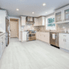 A kitchen with white cabinets and tile floors.